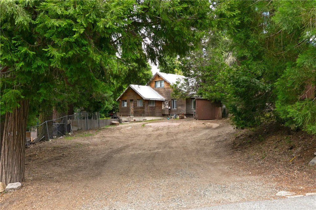 Charming Twin Peaks Cabin – Investor’s Special! Tucked away on a mostly flat 7,500 sq ft lot surrounded by towering trees, this vintage Twin Peaks cabin is full of potential. Located in easy walking distance to local dining, shopping, gym and parks, it offers the perfect blend of seclusion and convenience. Even better—it's just a few blocks from Highway 189, making it an ideal weekend getaway or commuter-friendly retreat.
The main level features two bedrooms and one bath, plus a cozy sleeping loft currently set up with two additional sleeping areas. The living room boasts a rustic stone fireplace, warm wood paneling, and classic cabin character throughout. The charming kitchen includes plenty of storage and a separate laundry area. Enjoy level entry from the street with ample room to expand or add a garage. With a little TLC, this four-season cottage could become your perfect mountain escape—or a smart investment opportunity. Priced to sell this season—don’t miss your chance. Make your offer today!