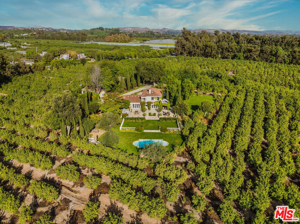 Welcome to Villa Amodei: A Masterpiece of Italian Elegance and Opportunity - Nestled on 28.73 acres of verdant, rolling lemon orchards, Villa Amodei is a bespoke Italian villa that epitomizes refined luxury and extraordinary potential. This generational estate seamlessly blends timeless sophistication with unparalleled income-generating opportunities, all within a serene, private haven with breathtaking panoramic views. A Residence of Distinction - The meticulously designed gardens, inspired by the famed Piranhurst Estates in Montecito, set the tone for this exceptional property. The main residence, remodeled in 2020, features four spacious bedrooms and three-and-a-half elegantly appointed bathrooms. The open-concept living spaces include a formal dining room illuminated by an exquisite iron chandelier and a chef's kitchen outfitted with top-of-the-line Thermador appliances, including a built-in refrigerator and freezer, as well as a Viking stove and microwave. Custom cabinetry and a center island elevate the culinary experience, making these spaces perfect for both daily living and grand entertaining. The master suite is a private sanctuary, boasting a double-sided fireplace, a private balcony with sweeping views of the gardens and surrounding mountains, and a spa-inspired en-suite bathroom with a soaking tub and a generous walk-in closet. Expansive windows throughout the home frame the stunning vistas, creating a seamless connection between the indoors and outdoors. Resort-Style Outdoor Living - The estate's outdoor spaces are equally remarkable, with two acres of terraced landscaped gardens, tranquil fountains, and Mediterranean-inspired greenery. Over 5,000 lemon trees enhance the estate's beauty and productivity. A luxurious lap pool, flanked by two stone cabanas with guest restrooms, offers an ideal setting for relaxation or entertaining. Design Excellence by Jennifer Amber and Celebrity Master Illusionist Ivan Amodei - Crafted by renowned designer Jennifer Amber, the home embodies livable elegance. Known for her work with celebrity clients and features in Architectural Digest, Jennifer's design seamlessly marries timeless sophistication with everyday comfort, ensuring every space is as functional as it is beautiful. Income Potential and Development Opportunities - Villa Amodei is not only a luxurious retreat but also a lucrative investment. The property has generated over $412,000 in revenue for 2024 with part-time operations. With full-time management, we estimate the property could generate over $1 million annually. 6201 Old Balcom Canyon Road: A Rare Offering - Whether you dream of an opulent private retreat or a high-performing investment property, Villa Amodei offers a unique combination of both. From its stunning vistas and world-class amenities to its boundless opportunities for expansion and revenue generation, this estate redefines luxury living. Experience the beauty, privacy, and potential of Villa Amodei, a true masterpiece.