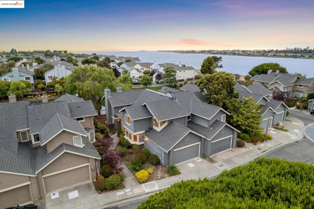 Tucked into one of Alameda’s most serene enclaves, this Bay Farm Island home blends elevated elegance with West Coast ease. The remodeled 3BD/2BA townhouse sits on a private stretch of the lagoon (with dock easement), where a graceful willow tree casts reflections across the water and waterfowl swim by. Inside, the vibe is refined, coastal, and quietly luxurious. Box beam ceilings and wide-plank hardwood floors anchor the large living room, while a built-in wet bar and large lagoon-side sliding doors invite in the water view and allow for easy indoor-outdoor living. The kitchen is equal parts functional and stylish, with new stainless steel appliances (including a wine fridge) and a built-in linen-upholstered settee inviting guests to lounge and entertain the cook. Upstairs, the primary suite is a calm retreat with terrazzo tile flooring, a basketweave stone fireplace, and nuetral spa-inspired tones. Even the staircase features luxury woven carpet, adding warmth and texture. There is plenty of storage in ample closets and a large two-car garage. With access to community amenities including a pool and hot tub, this lagoon-side home offers a rare blend of modern comfort, thoughtful design, and natural beauty.
