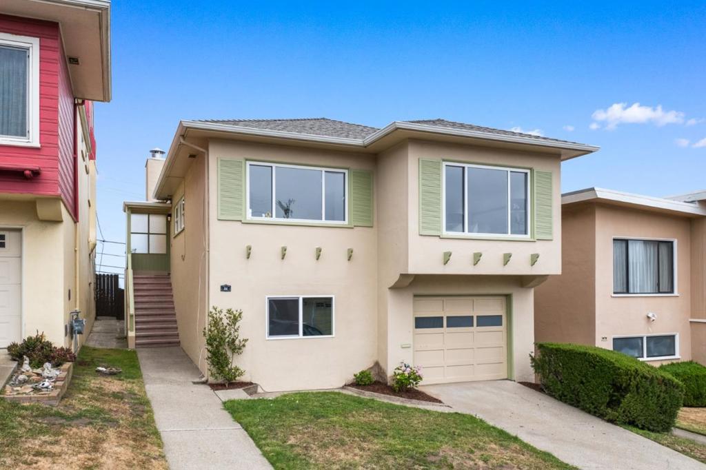 Located in Westlake, this classic mid-century home offers ocean views, architectural charm, and urban convenience. The split-level design captures Pacific Ocean views and glimpses of the Golden Gate Bridge spires. Just one block from ocean-front Palisades Park, the setting is both scenic and walkable. Inside, freshly painted interiors and random plank hardwood floors reflect timeless style. The living and dining area features a picture window, wood-burning fireplace, and halo chandelier. The kitchen has tile countertops and full-height backsplashes.. Three bedrooms and two baths include a primary bedroom with walk-in closet and direct access to one of two side-by-side baths. The lower level offers a large recreation room and flexible-use room, and access to an oversized tandem garage with laundry and yard access. A level rear yard offers space for entertaining, gardening, or play. Near Westlake Shopping Center, BART, and commute routes to SF and Silicon Valley.