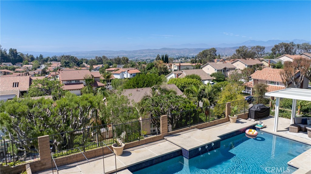 *VIEW * VIEW * VIEW * 6691 E. Smokewood Circle is a beautifully upgraded home ideally located on a corner lot in one of Anaheim Hills’ most desirable neighborhoods. This modern masterpiece blends luxury, functionality, and breathtaking views in every detail. Step inside and discover a unique split-level layout designed for flexible living. On the entry level, you’ll find a spacious in-law suite complete with its own fireplace, private en-suite bathroom, and direct access to the backyard oasis—perfect for multi-generational living or guest privacy.
Upstairs, the oversized primary suite impresses with vaulted ceilings, a large walk-in closet with custom built-ins, and serene mountain views. The fully renovated chef’s kitchen is a showstopper, featuring a 6-burner dual-oven range with griddle, waterfall-edge countertops, chrome fixtures, an AquaTru reverse osmosis alkaline water purifier, a quick-cleaning glass washer, and smart organization solutions like cabinet towers and pull-out shelves.
The open-concept living area is anchored by a stunning 16-foot sliding glass door that seamlessly connects indoor comfort with panoramic outdoor views of sunsets and rolling hills—perfect for entertaining or unwinding after a long day. Throughout the main level, you’ll enjoy durable and stylish luxury vinyl flooring, while the epoxied garage floor adds a sleek touch and easy maintenance.
The backyard retreat features a sparkling pool and spa, plus a new aluminum patio cover with built-in lighting, electrical outlets, and a ceiling fan—ideal for year-round outdoor enjoyment. Minutes from the golf course, Santa Ana Mountains Trail, and top-rated schools.