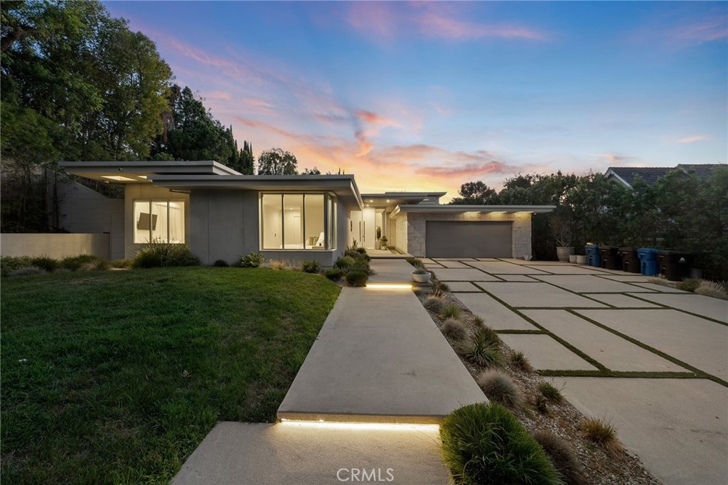 Set back from the street, behind private gates, this newer-construction mid-century modern masterpiece sits on a sprawling 18,000+ sf lot in prime Encino. Double doors open to reveal a warm and inviting interior, showcasing natural woods, imported stone and dramatic floor-to-ceiling walls of glass that bathe the space in natural light. Enjoy a spacious open-concept floor plan that is accentuated by lofty 14’ ceilings and gorgeous oak flooring. A culinary enthusiast's dream, the gourmet kitchen is equipped with high-end Miele appliances, a massive island with a breakfast counter, butlers pantry and wet bar with a pass through window to the patio. Both the living and family room have an oversized Fleetwood pocket door that disappears into the wall, seamlessly extending your living space outside for effortless entertaining and a true indoor-outdoor lifestyle. A sun drenched formal dining room and glass-enclosed office complete the main living space. Spread throughout the first floor you’ll find four en-suite bedrooms, including a stunning primary suite that features dual walk-in closets and a spa-inspired bathroom, complete with a soaking tub, large rainfall shower, smart toilet and double vanity. A sleek floating staircase leads you up to an additional ensuite bedroom, currently utilized as a fitness room, the space boasts a sauna and steam shower. Enveloped by mature privacy hedges, the spacious backyard retreat is a serene escape designed for both relaxation and entertaining. Highlights include a sparkling pool/spa, sports court, putting green, outdoor kitchen, built-in fire pit and ample patio space for al fresco dining. Additional amenities include a laundry room, smart home features like integrated speakers and motorized blinds, a state-of-the-art security system, plentiful storage space and a two-car garage with an EV charging station. This prime South of the Boulevard location is in the heart of Encino, within an excellent school district and just moments away from everything the Valley and Westside have to offer.