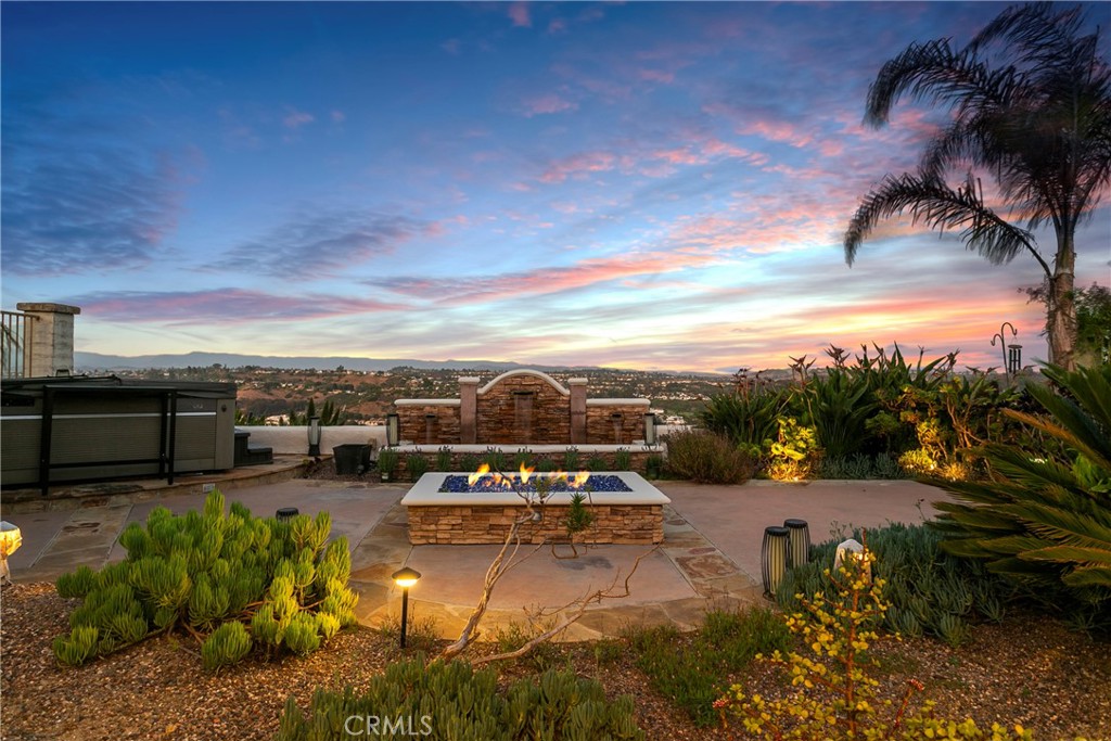 Perched on a coveted single-loaded street just minutes from the coast, this impressively redesigned residence in Niguel Summit showcases panoramic views stretching from Saddleback Mountain to the Pacific Ocean. Meticulously updated inside and out, this home pairs high-end modern finishes with relaxed Southern California elegance. Step through custom double entry doors into a light-filled interior where vaulted ceilings and contemporary fixtures make an unforgettable first impression. Luxury vinyl flooring flows throughout, complemented by a dramatic black stacked-stone accent wall and a reimagined staircase with sleek horizontal railings. The heart of the home is the chef’s kitchen, a striking space featuring quartz countertops, an oversized island with seating, commercial-grade stainless steel appliances including a six-burner cooktop, double oven, and wine fridge. The entire home has been re-piped with PEX plumbing. The kitchen opens seamlessly to the formal dining area and the inviting family room, centered around a stylish fireplace and views out to the backyard. A standout feature: the custom wine cellar nestled beneath the staircase, complete with a wrought iron-inspired door offering both form and function for entertaining in style. Upstairs, the primary suite offers vaulted ceilings and captivating vistas, along with a luxurious spa-like bath featuring a freestanding soaking tub, walk-in rainfall shower, and refined designer touches. Two additional guest bedrooms and a fully remodeled guest bath complete the upper level. Designed for indoor-outdoor living, the backyard is an entertainer’s paradise featuring an expansive covered patio, built-in outdoor kitchen, firepit, lush landscaping and a private hot tub, an ideal retreat to relax and unwind while soaking in the incredible views. Ideally situated above Monarch Beach and just minutes to Dana Point Harbor, Salt Creek Beach, and the vibrant art and dining scene of Laguna Beach, this home delivers the very best in elevated coastal living.