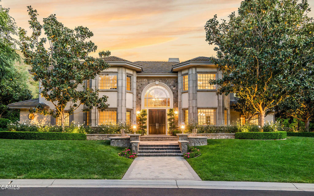 Nestled on a quiet cul-de-sac, in Guard Gated North Ranch Country Club Estates, this French Provincial-style estate is a masterclass in refined living and timeless elegance on a sprawling over 1 acre lot. A grand mahogany front door, capped by a beveled glass window, and framed by lush rose bushes, hedges and magnolia trees introduce you to the luxury and serenity within. The main level features chiseled-edge Versailles-pattern travertine floors throughout the sophisticated spaces. A step-down media room, with blackout drapes and an onyx-topped wet bar is perfect for movie nights. A library offers a quiet retreat, while a spacious office with built-in desks provides flexibility--easily converted into a bedroom suite. An additional main-level bedroom includes an accessible, age-in-place bathroom, ideal for multigenerational living. The heart of the home is the impressive cook's kitchen. Finished with onyx countertops, huge island, carved limestone sink and hammered-nickel prep sink, the space is equipped with high-end appliances, including four ovens, and a custom limestone/pewter hood - all tailored for serious cooks. Custom cabinetry includes a pop-up mixer cabinet and top lighting. A butler's pantry and over-sized breakfast nook, complete the space. A dining room with a glowing ceiling and a spacious family room with coffered ceilings and a marble fireplace are perfect settings for memorable meals, parties and relaxation. A 350-bottle capacity wine room is a collector's dream! The primary suite is a dream with its carved wood and marble fireplace, sitting area and dual walk-in closets. The en-suite bath features a freestanding tub, large glass and marble shower with Waterworks waterjet designed wall, and built-in vanity--with views of the beautiful grounds. Two additional guest suites with well-appointed ensuite baths round out the upstairs. The backyard is a showstopper. Nearly 1,000 blooming rose bushes create a dramatic backdrop against the hillside of this paradise. A Pebbletec salt water pool and spa sit in the center of an oasis that includes an elevated fireplace pavilion, built-in artisan BBQ area and multiple seating areas. The entire space is surrounded by vibrant landscaping, creating an elegant outdoor retreat. From the moment you arrive, the home makes a statement - elegant, warm, and impeccably maintained. In the heart of one of Westlake Village's most idyllic neighborhoods, this home is built for real life living in luxury and convenience.