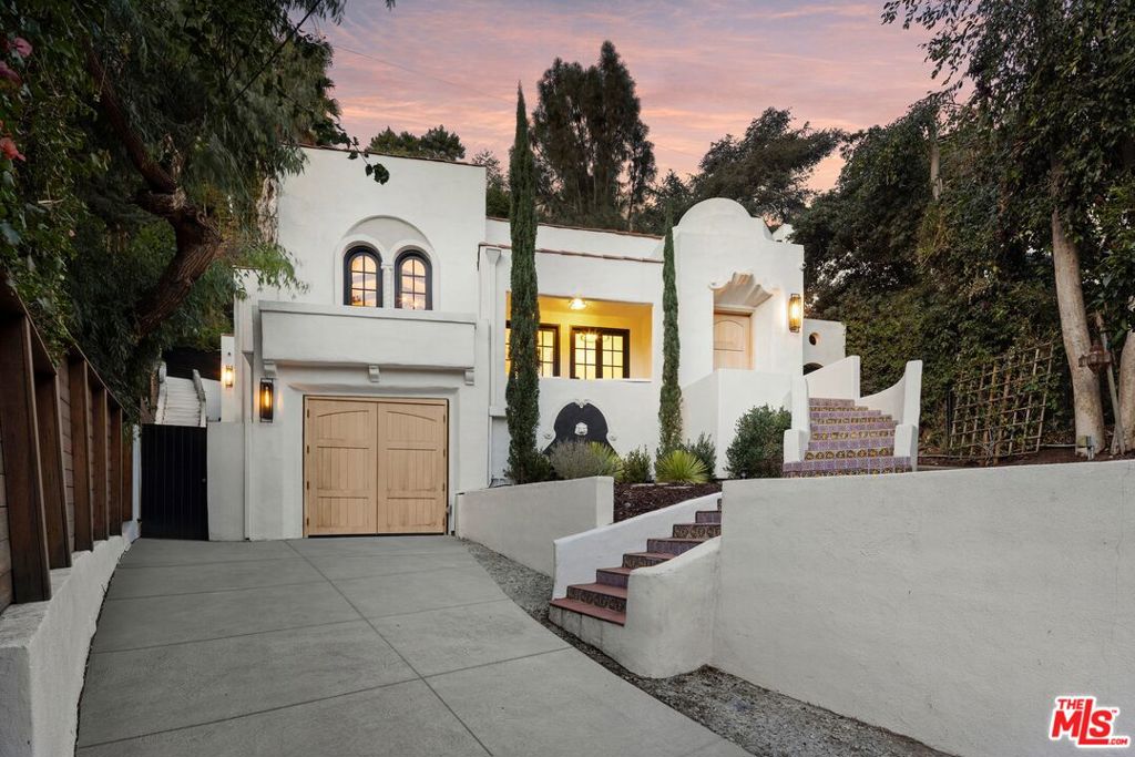 Tucked away on a quiet cul-de-sac, this 1923 Spanish Colonial with a Tuscany Flair blends timeless character with modern comforts, offering the perfect balance of privacy and convenience just moments from the Sunset Strip and iconic Chateau Marmont. Elevated above the street and framed by majestic trees, the home feels like a true retreat while staying connected to the vibrant heart of Los Angeles. Each of the three bedrooms opens directly to its own outdoor space, creating seamless indoor-outdoor living ideal for both quiet relaxation and inspired entertaining. Sunlight fills the interiors, highlighting original architectural details that harmonize beautifully with recent upgrades. Freshly painted inside and out, the home features restored wood floors, tile-accented foyers and terraces, and newly installed mahogany entry and garage doors that add warmth and craftsmanship. The updated kitchen is a chef's delight with marble countertops, a Wolf range, and a Sub-Zero refrigerator. The garage has been thoughtfully converted into a luxury gym, also perfect for a private office or studio. Modern upgrades, enhanced wiring, and a built-in gas grill make everyday living effortless. A terrace and private deck offer serene outdoor escapes with stunning sunset views, surrounded by trees that create a tranquil, retreat-like environment. Just minutes from world-class dining, entertainment, and culture, walking distance to the Sunset Strip. This rare offering captures the essence of Laurel Canyon living, a sanctuary of history, beauty, and comfort in one of Los Angeles's most iconic neighborhoods.