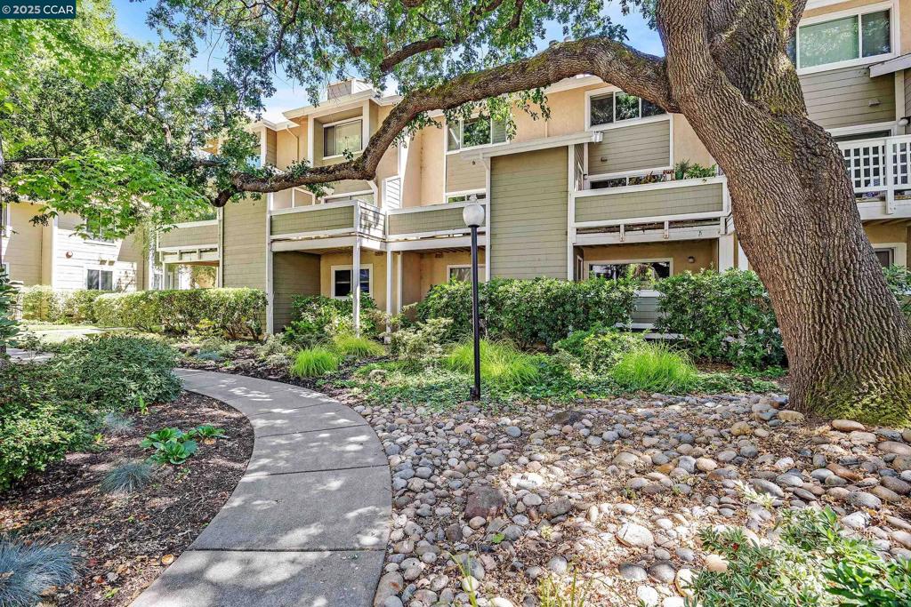 This spacious and light-filled upper-floor home in the sought after Carriage Place complex pairs a welcoming space to come home to with modern conveniences. Step through the foyer and into the open living and dining area, where ample windows and a large slider to the balcony bring in plenty of natural light. A cozy fireplace and a perfect nook for a bookcase or media setup as well as a downstairs half bath add warmth & function. The balcony offers a peaceful view of the green areas and one of the two community pools, plus additional storage space. The remodeled kitchen features stone countertops, ample cabinetry, and all-new appliances including a French-door fridge,perfect for everything from quick bites to gourmet meals. Upstairs, two ensuite bedrooms offer lots of closet space and potential room for guests, a home office, or your own private fitness room. Updated baths have modern vanities, new lighting and mirrors, a shower-over-tub in one suite, and an expanded shower in the other. Energy saving features include in-unit laundry, dual-pane windows with custom shutters, and a new furnace and AC. That combined with low HOA dues, and a location close to shopping, Walden Park, and both Walnut Creek and Pleasant Hill BART stations