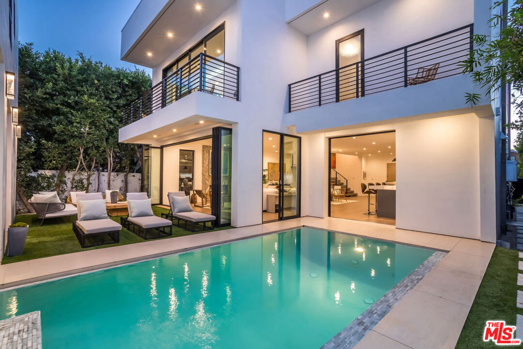 This exceptional contemporary home, located on a prime street in the coveted Melrose Village, seamlessly combines modern design with warm, inviting spaces. The 4-bedroom, 4.5-bath main house features a zero-edge pool, spa, covered patio with a fireplace, turf yard, and a versatile separate guest retreat. The open floor plan effortlessly connects the living room, dining area, and kitchen, creating a perfect setting for entertaining or everyday comfort. High-end finishes include Poggenpohl cabinetry, Miele appliances, and Fleetwood pocket doors. A first-floor en suite bedroom doubles as a sophisticated office space. A dramatic staircase leads to a second-floor family room with Hollywood Hills views. The spacious primary suite offers a luxurious bathroom, two walk-in closets, a fireplace, and a private balcony. Two additional en suite bedrooms feature custom built-in closets and private balconies. A separate rear structure offers flexibility as a guest suite, office, gym, or recording studio. The harmonious blending of natural elements, facilitated by large windows, expansive glass doors, and thoughtful landscaping, creates a seamless connection between indoor and outdoor living. Additional highlights include built-in speakers, central vacuum, integrated security, and an oversized two-car garage. Situated on a highly desirable street, this home is just moments from The Grove, Melrose shops, and popular dining spots, a rare opportunity to enjoy modern living in one of LA's most coveted neighborhoods. List price is for unfurnished, please contact for furnished price.
