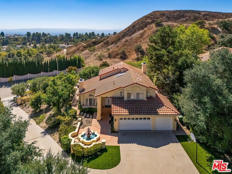 Come for the view. Stay for the quiet. Poised on a gated 0.72-acre knoll on a cul-de-sac in coveted Canyon Crest, this light-filled residence captures sweeping panoramas of the San Fernando Valley.  Inside, 2,669 sq ft of freshly painted living space showcases brand-new French oak wood floors, a dramatic skylit foyer, and soaring vaulted ceilings in both the living room and the primary suite. Plantation-shuttered windows and French doors bathe the formal living and dining areas in natural light and invite seamless flow to the patio. The spacious kitchen is ready for gatherings with newer stainless-steel appliances, a center-island cooktop, and an airy breakfast nook, all open to the family room - complete with classic fireplace, built-in entertainment center, and wet bar. Up the curved staircase, double doors reveal a retreat-style primary suite where sunrise vistas greet you each morning. The ensuite bath offers large walk-in closet, dual sinks, a glass shower, and a soaking tub framed by treetop, mountain, and city-light views. Two additional bedrooms and full bath are upstairs, one bedroom and bath down, providing flexible space for family, guests, or home office needs. Outdoors, you can stroll the expansive 31,218 sq ft lot. through serene, nature-inspired settings as well as patios overlooking the valley - offering room for al-fresco dining, gardening, a future pool, or maybe a horse. A three-car garage includes a sound-insulated, climate-controlled studio ideal for music production, media editing, or a quiet office. All of this is nestled north of Rinaldi and west of Balboa, moments from top schools, horse trails, hiking trails, and freeway access. Located just one block from the private Canyon Crest area and only minutes from O'Melveny and Bee Canyon Parks, the home is ideally situated for outdoor enthusiasts.  Rarely does a property marry privacy, scale, and views like this - come experience Lone Oak Drive for yourself.