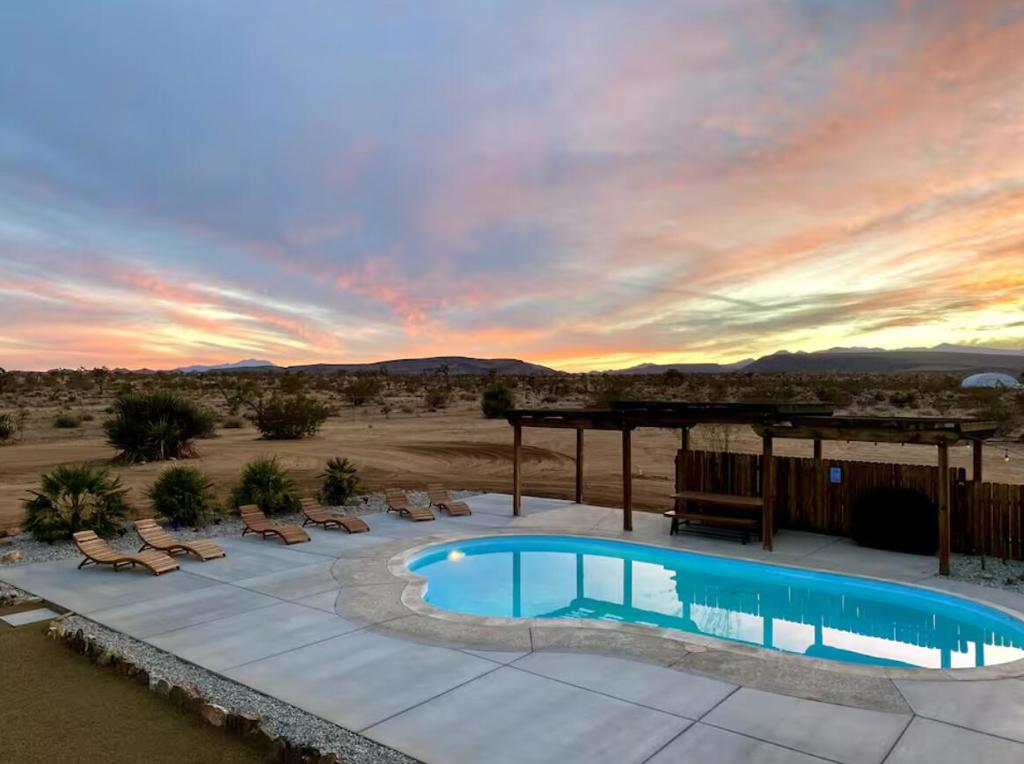 Large designer pool home remodeled from top to bottom. A successful STR for several years. . Situated on 2.5 acres in north Yucca Mesa with panoramic views. Vistas of Mt. San Gorgonio with seasonal snow caps. Views of Goat Mtn, the Big Horn Mtns, and Mt Bartlette surround this oasis set among a sea of beautiful Joshua Trees. 3-bedroom, 3-bath with 1,848 sf & 2 car garage with inground pool & spa. Entryway leads to a covered front patio with woven chandeliers, custom flooring, southwestern cactus arrangement and a long table for dining alfresco. Spacious living room with white smooth walls, ceiling & flooring. Wood Burning stove and mini-split hvac. Kitchen with electric stainless steel appliances, recessed lighting, butcher block counters, breakfast bar, dual basin sink, and ample cupboards and cabinets. Huge second floor master bedroom with laminate floors, arched ceilings, soaking tub, mosaic design wall, uplifting views, doorway to exterior deck and stairs to the patio. Downstairs bedroom with office alcove, door to patio, private bathroom with glass shower and tile. Sprawling concrete patio encircles the inground pool, with pergola, covered BBQ. hammocks, loungers, and separate firepit island. Enjoy starry nights with friends under the milky way. Short trip to all amenities. 16 miles to the Joshua Tree National Monument where about 3 million tourists visit annually. 43 miles to Palm Springs. 131 miles to LA. Don't Wait - Call Now!