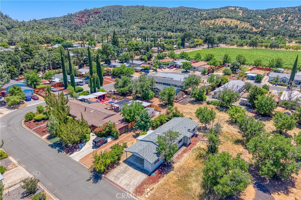Live beautifully in this open and spacious 2 bedroom & 2 bath home in Clearlake Oaks. The approximately 1344 square foot is super welcoming and practical with a great floorplan including vaulted ceilings in living areas and master bedroom. With a green belt in the back and on the side of the home, experience a feeling of living large with fantastic views of the hillside vineyards. The living areas have an open concept living/dining room, a large kitchen with ample cabinetry and counter space, 2 generously sized bedrooms, plus a large convenient inside laundry room. The AC/Heating unit was replaced in 2024 and the roof is nearly new - installed in 2023. Other major component such as the water-heater is about 2 years new. Located in the well planned community of Orchard Shores, with wide streets, underground utilities, a club-house, seasonal pool and more. Covered parking in a good size car-port. A large storage room provides excellent storage space. Easy access into and around the home - space for planting a garden, a few fruit trees and backyard fun. Come take a look! Excellent value considering almost brand new roof, AC/Heat and Water-Heater. With very little effort could be a real showcase. Fantastic opportunity for retirees looking for low cost living, rental investment or a vacation home.