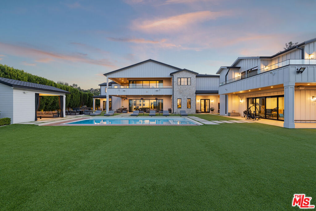 Welcome to this unparalleled modern farmhouse masterpiece, nestled south of the Boulevard in Encino, where grandeur meets charm behind private gates. This stunning, newly constructed estate sprawls across a spacious 1.35-acre lot, offering a secluded sanctuary on a quiet cul-de-sac. As you approach the grand estate, an extensive driveway leads you to an impressive 13,000 square feet of refined luxury. The large foyer greets guests with dramatic, soaring ceilings and seamlessly flows into the spacious living rooms. The massive gourmet kitchen features double islands and a cozy breakfast nook, a butler's pantry that enhances the dining experience, and opens up to breathtaking views of the meticulously landscaped grounds. The estate is a haven of entertainment and relaxation, comprising 8 exquisite bedrooms, 12 luxurious bathrooms, and 2 dedicated offices. The two-story guest house, along with a covered cabana with its own bathroom, offers ample space for guests, ensuring privacy and comfort. Indulge in the temperature-controlled wine cellar, state-of-the-art home theatre, and an outdoor kitchen perfect for alfresco dining. The property also features a private gym, a sports court for the active lifestyle, and a saltwater pool for tranquil leisure. The estate is complete with a 4-car garage, generator, and guard-house, ensuring utmost security and convenience. This modern farmhouse estate is a statement of luxury and sophistication, offering endless entertainment opportunities and a lifestyle of unparalleled comfort and elegance. Don't miss the chance to own this magnificent property, a true masterpiece of modern luxury and charm in the heart of Encino.