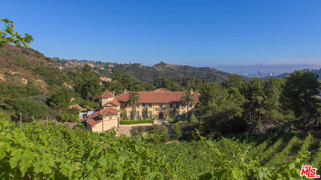 75 Beverly Park Lane is an extraordinarily regal estate for the modern era, set behind gates within exclusive Beverly Park Estates. With fireplaces sourced from European castles, soaring vaulted ceilings and triple crown moldings, this home sits on 5.8 acres, 3 of which are covered with merlot vines that produce up to 150 cases per year. Enter double-doors to the two-story foyer, which opens to the backyard's pool and lounge area with broad treetop views. The kitchen boasts SubZero and Wolf appliances, while the dining room leads to the wine cellar, which doubles as a home theater. The second level features an office, staff quarters and 8 ensuite bedrooms, including the master suite with dual baths, dressing rooms and gym. Featuring a 4-car garage and motor court with ample parking, the home offers the rare chance to own a private vineyard within one of the most desirable enclaves in Beverly Hills.