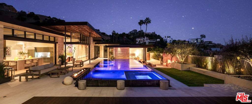 Experience the pinnacle of modern luxury in this private estate nestled on a flat half-acre lot in the prestigious Doheny Estates. Designed by renowned architect Jay Vanos, this state-of-the-art residence spans nearly 7,000 sq. ft., seamlessly blending earth-tone modern aesthetics with dramatic reclaimed barn wood ceilings for an ambiance of warmth and sophistication. Behind a gated motor court, this exceptional home offers a private theater, gym, wine cellar, and a three-car garage. The highlight is the oversized zero-edge pool, perfectly positioned to showcase breathtaking views. Crafted by Bowery Design Group, this architectural estate embodies tranquility, innovation, and high-design living at its finest. Don't miss this rare opportunity to own a true resort-style retreat in one of LA's most coveted neighborhoods.