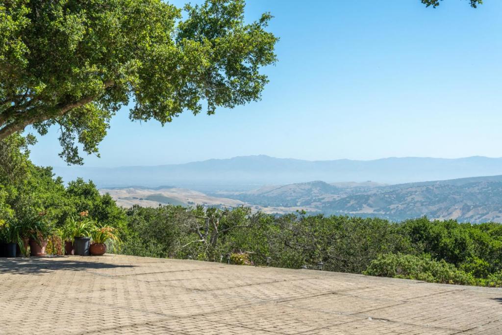 Unwind on your very own hilltop oasis, sun-drenched and overlooking Castle Rock, Corral De Tierra Country Club and the greater Salinas Valley from one side of the house, and from another, gorgeous views of the Monterey Bay and Santa Cruz mountains. Peaceful and quiet, and on a dead end street, the home was constructed as a forever home, incorporating entertaining and open floor plan elements much ahead of its time. Experience soaring ceilings and open beams in the chef's kitchen, and a large island and bartop. The adjacent living area features an expansive layout, offering both space, and the feeling of togetherness, as experienced through multiple gathering areas, a dining area, wet bar area and a sunken fireplace seating arrangement. The primary bedroom suite affords massive space, an extra large shower and views across the Pacific. 3 additional guest rooms, a shared full bath, and a powder room near the front entry way, complete this perfect entertainer's design.