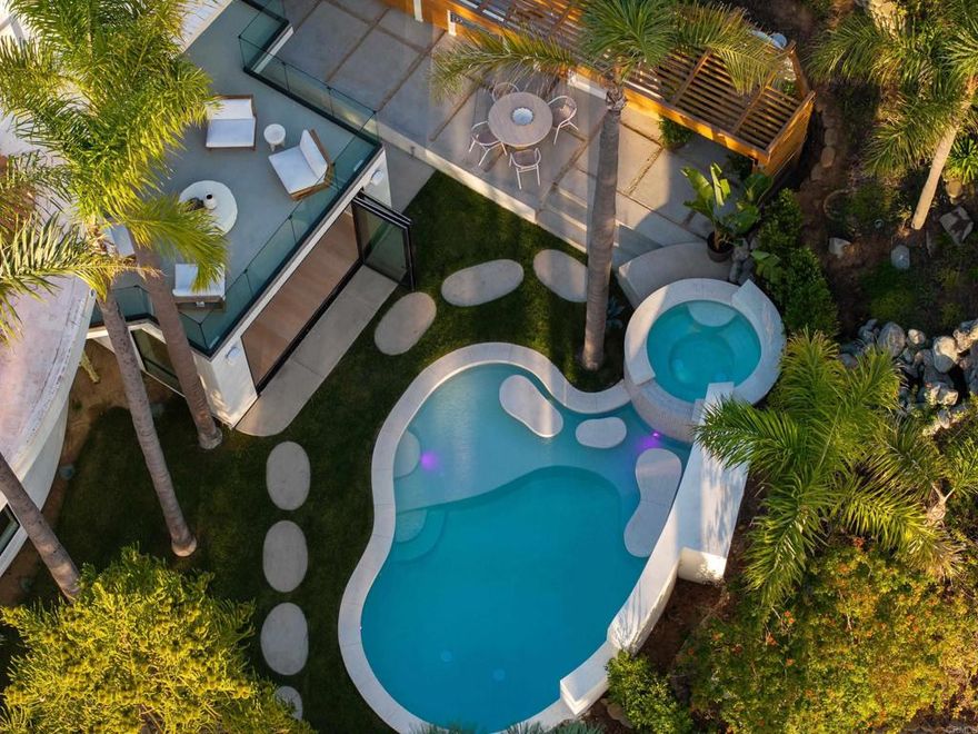 With a substantial $360,000 price adjustment, this breathtaking Rancho Del Mar sanctuary—newly constructed and privately nestled on a fully fenced, gated one-acre lot at the end of a quiet cul-de-sac—offers exceptional value for a home of its caliber. Designed and curated by Renouveau Hom, the residence blends sculptural modern luxury with an organic coastal-ranch spirit. Roman clay walls, honed Calacatta Viola marble, custom oak cabinetry, dramatic arches, and warm natural wood floors create a space that feels both elevated and inviting.  A grand entry introduces the home’s signature “wow” moment: a soaring rotunda with a two-story domed wood ceiling and sculptural fireplace anchoring the airy indoor–outdoor flow. The chef’s kitchen—with an oversized honed marble waterfall island often described as “continent-like,” Sub-Zero refrigeration, and Monogram appliances—opens seamlessly to the living spaces and outdoor terraces.  Five spacious bedrooms include dual primary suites, one on each level, ideal for multi-generational living. The lower-level suite enjoys its own private entrance, while the upper primary captures serene views over the resort-style saltwater pool and spa. Four bedrooms feature private outdoor spaces for morning coffee or sunset relaxation.  Designed for effortless entertaining, the property boasts an outdoor kitchen with pizza oven, grill, and beverage center; fire-pit and lounge areas; a hot/cold outdoor shower; and a large flat grassy yard for children or pets. Mature trees, lush privacy, and low-maintenance landscaping frame the stunning pool and spa, creating your own SoCal retreat.  Additional highlights include designer lighting throughout, a 4-car garage with EV charging, ample guest parking, a newly poured driveway with separate RV gate, and space ideal for a bocce court.  14847 Vista Del Oceano is a rare offering—an artfully crafted, never-lived-in sanctuary that feels worlds away yet close to everything - beaches, restaurants, boutiques and freeway​​‌​​​​‌​​‌‌​​‌​​​‌‌​​​‌​​‌‌​​​‌​‌​​​‌‌​ access.