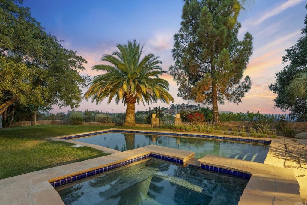 Welcome to 28889 Anderson Court, an enchanting Spanish Mission-inspired residence perfectly sited on 2.14 acres for the ultimate in privacy. From the moment you arrive via the long, private driveway and porte-cochère, you’ll feel a sense of tranquility surrounded by lush landscaping, mature specimen palms, and postcard-perfect vistas. Soaring views to the south and west create an incredible light orientation and a front-row seat to nature’s beauty—complete with abundant wildlife and magical ocean and sunset views. The elevated setting, perched at 1750 feet above sea level, offers a unique microclimate, ideal for vibrant landscaping and future expansion opportunities. Inside, the home spans four bedrooms, including a spacious primary suite with panoramic views and a generous closet. Designed with flexibility in mind, the property easily lives as a three-bedroom main home plus an attached 1000sf guest suite—perfect for multi-generational living, hosting guests or as a partitioned rental unit or home office. The suite features its own private entrance, bedroom, bathroom, office and laundry hookups, plus pre-installed 220 electric and plumbing for a stove, fridge, sink, chandelier and space for a breakfast lounge. The main level boasts a grand living room with vaulted ceilings and a cozy fireplace, an oversized dining room that opens to views of the pool and gardens, and a well-appointed kitchen flowing seamlessly into a generous family room with direct access to a spacious, covered outdoor loggia. Step outside and discover an entertainer’s paradise: a sparkling pool and spa, expansive sun patios, lush lawns for play, and a private viewing pavilion overlooking the grounds. Beyond the landscaped area, an unfenced portion of the lot offers exciting possibilities to add a tennis or pickleball court, vineyard, additional guest house, or private garden retreat. Additional features include an oversized three-car tandem garage with abundant storage, room to create a wine cellar, and timeless handcrafted stone exterior walls reminiscent of historic California missions. This exceptional property is located within Rimrock Estates, an exclusive, guard-gated community celebrated for its privacy, security, and breathtaking views. Known as one of the most desirable enclaves in North San Diego County, Rimrock Estates offers a serene retreat from city life while remaining just minutes from shopping, dining, and freeway access. The community is defined by its elevated lots with sweeping mountain and coastal vistas, stunning custom homes on large private parcels, and proximity to golf, equestrian facilities, wineries, and great schools. Combining luxury living with a strong connection to nature, Rimrock Estates delivers an idyllic setting for those who value privacy and beauty. This property is far more than just a home—it’s a sanctuary. Experience the perfect blend of classic architecture, peaceful living, and endless opportunity at 28889 Anderson Court.