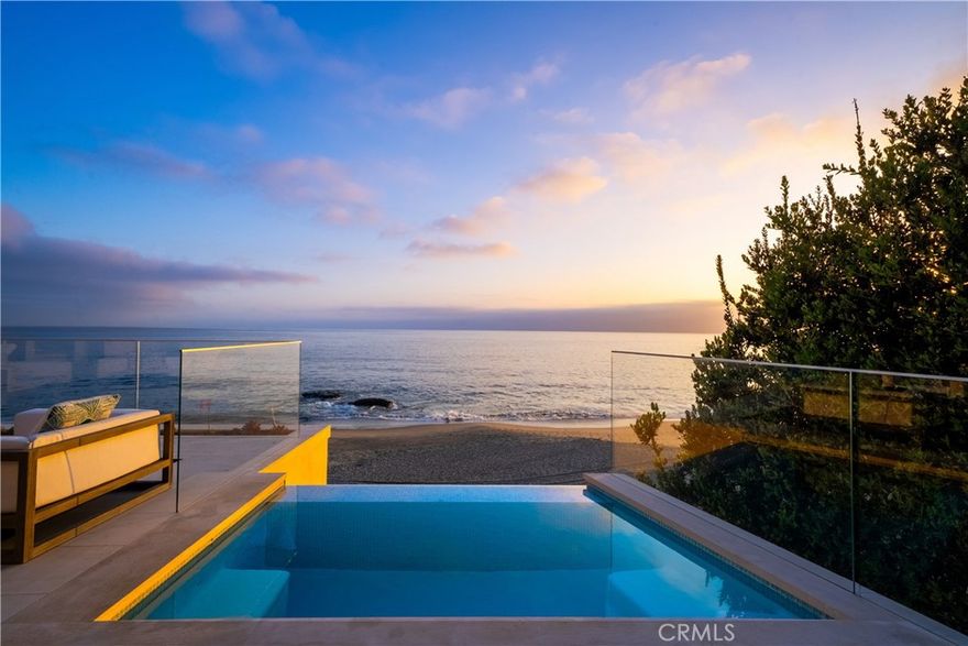 This is more than just a home; it’s a lifestyle. Your dream coastal retreat is a stunning contemporary estate nestled on pristine sands in Lagunita, one of a few gated beachfront communities in Laguna Beach. This magical setting features 270-degree panoramic ocean views encompassing Catalina Island in front, the Montage on the left, and Victoria Beach on the right. Whales nuzzle against the boulders in the center of your view, an incredible glimpse of the natural world at your doorstep. Designed by esteemed architect Stephen Thompson and renowned builder Tony Valentine, this residence represents the pinnacle of craftsmanship and style, where every detail reflects a commitment to quality and excellence. 
Ground up remodel in 2018, the home offers 6,738 sq ft of luxurious living space across four levels, meticulously crafted for both grand entertaining and intimate gatherings. The 54 feet of beachfront allow you to relish the serenity; outdoor living space offers direct community steps, beach access, on-deck infinity spa, Lynx grill, and al fresco kitchen. Expansive interior features four en-suite bedrooms, office, and a total of eight beautifully appointed bathrooms. Design details include four custom fireplaces swathed in onyx & marble, plus a one-of-a-kind stone mantel embedded with fossils. Nearly 12-foot-high ceiling in living room, unique among beachfront homes, add to the sense of space and drama. 
Dedicated entertaining space features a custom semicircular movie theater with unparalleled acoustics, billiard room with seated bar, 420-bottle wine cellar, video game room & bathroom, gym, locker room and steam/sauna. Gourmet kitchen is equipped with top-of-the-line Miele and Viking appliances with a bulthaup hood fan. Elevator serves all four levels and three-bay garage, a rarity in this exclusive area. This is truly the ultimate in Laguna Beach luxury — and it’s waiting for you.