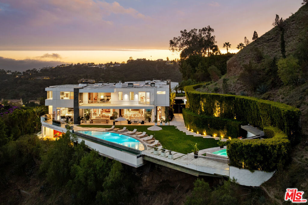 Privately perched on prestigious Bel Air Road behind a gated driveway, this one-of-a-kind estate delivers world-class design, total seclusion, and jetliner canyon and city views. This breathtaking architectural triumph redefines luxury living, with every inch designed to impress. Floor-to-ceiling windows flood the open-concept interiors with natural light, while automated retractable glass walls erase the line between indoor and outdoor living. The expansive entertainer's paradise features an infinity pool, spa, outdoor kitchen and bar, all set against a lush, sprawling grassy yard. Inside, every space is curated for both elegance and comfort with grand scale. A striking living room with a statement fireplace, a chef's kitchen with an oversized island and custom wood cabinetry, and a spa-inspired primary suite deliver a perfect balance of warmth and sophistication. A state-of-the-art home theater with an en-suite bar, a private studio, a 300-bottle glass wine cellar, and a fully equipped gym round out the next-level amenities. Surrounded by lush landscaping and mature trees, this estate offers unmatched privacy while being just minutes from world-class shopping, dining, and entertainment. A true architectural masterpiece and statement of prestige, this is a rare opportunity to own an unrivaled retreat in the heart of one of Los Angeles' most coveted enclaves.
