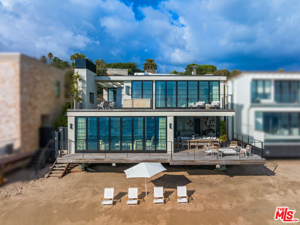 A perfect beachfront setting on a private road off Pacific Coast Highway puts this romantic contemporary residence front and center for sweeping views of the ocean, islands, and coastline from Point Dume to the sparkling lights of the Queen's Necklace. With a mid-century architectural pedigree and impeccable updates by Studio Bracket, the home is spacious, light-filled, and beautifully designed for indoor-outdoor living and entertaining. High, beamed ceilings, ocean-facing walls of glass, wood floors, fireplaces indoors and out, plus exquisite interiors by Steven Gambrel and artisan Venetian plaster work by Rex Pratt create an atmosphere of tranquil refuge by the sea. At the front of the house, a private, gated courtyard with sensational landscaping by Scott Shrader welcomes visitors and provides a quiet setting for conversation and contemplation. The home's interior, with timeless architectural details, puts the focus on comfort and views. On the main floor, there is a gorgeous formal living room with a fireplace and a full wall of ocean-facing glass doors that open to an oceanfront deck for entertaining, al fresco dining, and whale watching. The adjacent kitchen is a culinary triumph, with quartzite countertops, island with bar seating, top-of-the-line appliances, including a Lacanche double oven, generous custom cabinetry with imported English hardware, a butler's pantry, and a wonderful built-in dining nook with accordion windows that open completely to the oceanfront deck. Also on the main level is a lovely den/media room with built-in shelves, an office space, and a private side deck, perfect for yoga or afternoon tea. Gated steps from this deck lead to the sandy beach below. Upstairs, three en-suite bedrooms include the romantic primary, which enjoys panoramic views from inside and from the private lounging deck, which has an outdoor fireplace and Jacuzzi. The suite has a luxurious sitting area, a spacious walk-in closet with custom fixtures, and a spa-style bath with an extra-deep soaking tub and skylight.With approximately 50 feet of beach frontage, the home has a two-car garage plus additional guest parking and numerous features for safety and comfort, including home security, custom sound, air conditioning, heated bathroom floors, Waterworks fixtures, and much more. A home of rare quality in an ideal Central Malibu setting.