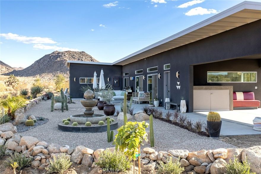 Contemporary Modern meets surrounding unbound nature in one of Joshua Tree’s most iconic areas. Meticulously designed and furnished 2-bed, 2-bath spread over nearly 2-Acres of land that doesn’t begin to explain the immersive, indoor/outdoor experience of this standout property. The main suite, for example, features sublime South African furniture, as well as a bright, oversized bathroom with huge soaking tub and a gated courtyard area through the sliding glass door for a private outdoor experience. In addition, a casita-style private entrance leads into the second bedroom, also with an en-suite full-bath. Sliding glass doors span the open floor plan of main living area, revealing a massive landscaped, event-ready, patio area and onward as far as the eye can see to boulder-laden National Park. Highly-rated short term rental due to the home’s many features plus a long list of unbeatable amenities that are included with the property, such as a hot tub, entertainment system, fire-table, security cameras, washer and dryer, and much more. Turnkey prepared to be taken over by new owners or retired into a long-term residence or superb primary residence with unmatched surroundings.