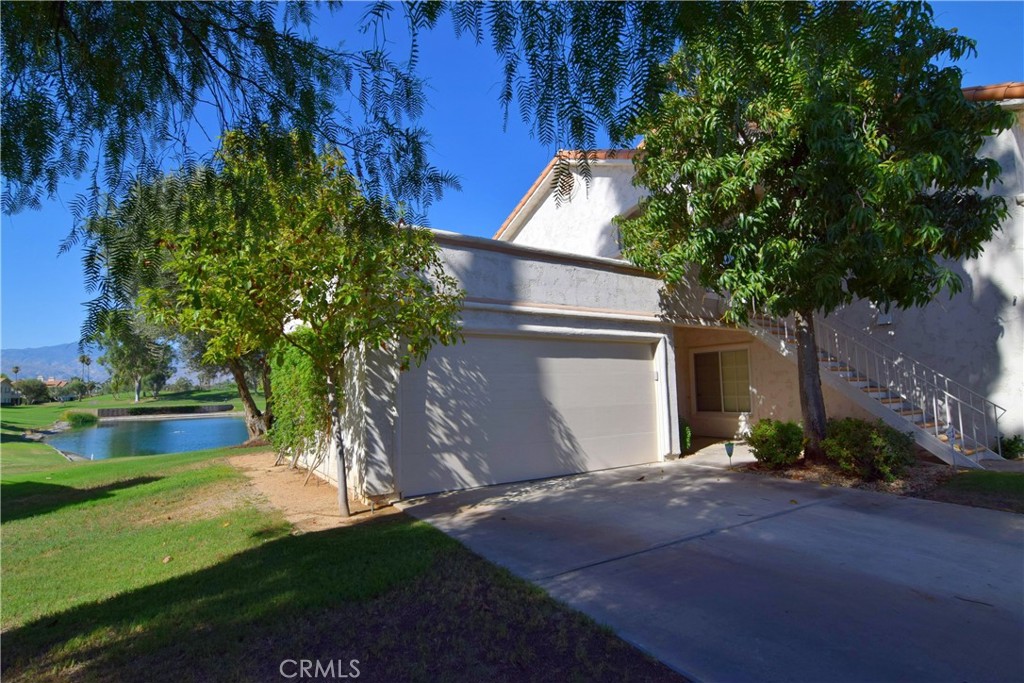 Stunning 2 bed, 2 bath ground-level condo with a sought after view of the lake at the 12th hole-- one of the premier and most desired locations on the golf course. Enjoy watching golfers hit tee shots and putt from this south-facing , single level unit. This updated home features a modern kitchen with quartz countertops, white shaker cabinets and stainless steel appliances. Other amenities include plantation shutters, and newer porcelain wood-style flooring and custom baseboards. Includes indoor laundry room, 2 car garage and a large private driveway. This end-unit home is perfectly positioned on a quiet cul-de-sac and just across the street from one of the many pools! The association offers exceptional amenities, including a gym, tennis courts, pickleball, and a active clubhouse. Experience luxury living in a serene, sought-after setting! Furnishings available. Strong vacation rental history and book of business may be available if interested.