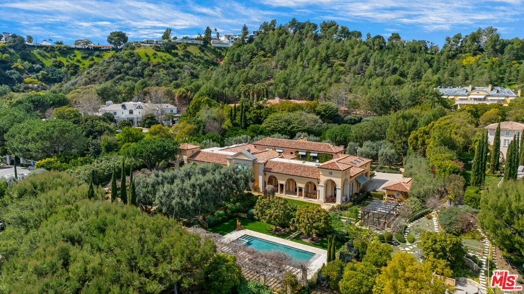 Magnificent Mediterranean Estate on expansive grounds. Dramatic Palladian-style entry leads to a grand living room with soaring ceilings and stone fireplace. Large formal dining room with French doors that opens out to an enormous veranda, perfect for al fresco dining. Unique bar/lounge area and wonderful cook's kitchen. The home is built around two romantic courtyards that offer stunning interior views and sunlight. Rare, and much sought after, primary suite located on the main level of the residence. Enormous dual closets and dual offices comprise the living quarters. There are two en suite bedrooms upstairs with kitchenette. Sited on over nearly 2.7 acres of lush and enchanting grounds featuring a stunning swimmer's pool, formal gardens and mature fruit trees. Gated, with a sweeping gravel motor court and ample parking. Located in the premiere community in Los Angeles, Beverly Park, the gold standard of luxury living.