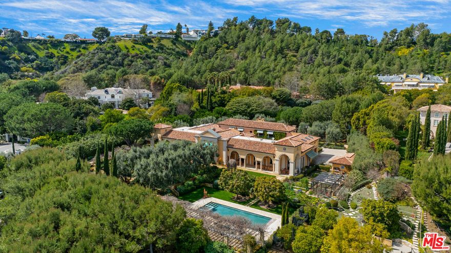 Magnificent Mediterranean Estate on expansive grounds. Dramatic Palladian-style entry leads to a grand living room with soaring ceilings and stone fireplace. Large formal dining room with French doors that opens out to an enormous veranda, perfect for al fresco dining. Unique bar/lounge area and wonderful cook's kitchen. The home is built around two romantic courtyards that offer stunning interior views and sunlight. Rare, and much sought after, primary suite located on the main level of the residence. Enormous dual closets and dual offices comprise the living quarters. There are two en suite bedrooms upstairs with kitchenette. Sited on over nearly 2.7 acres of lush and enchanting grounds featuring a stunning swimmer's pool, formal gardens and mature fruit trees. Gated, with a sweeping gravel motor court and ample parking. Located in the premiere community in Los Angeles, Beverly Park, the gold standard of luxury living.