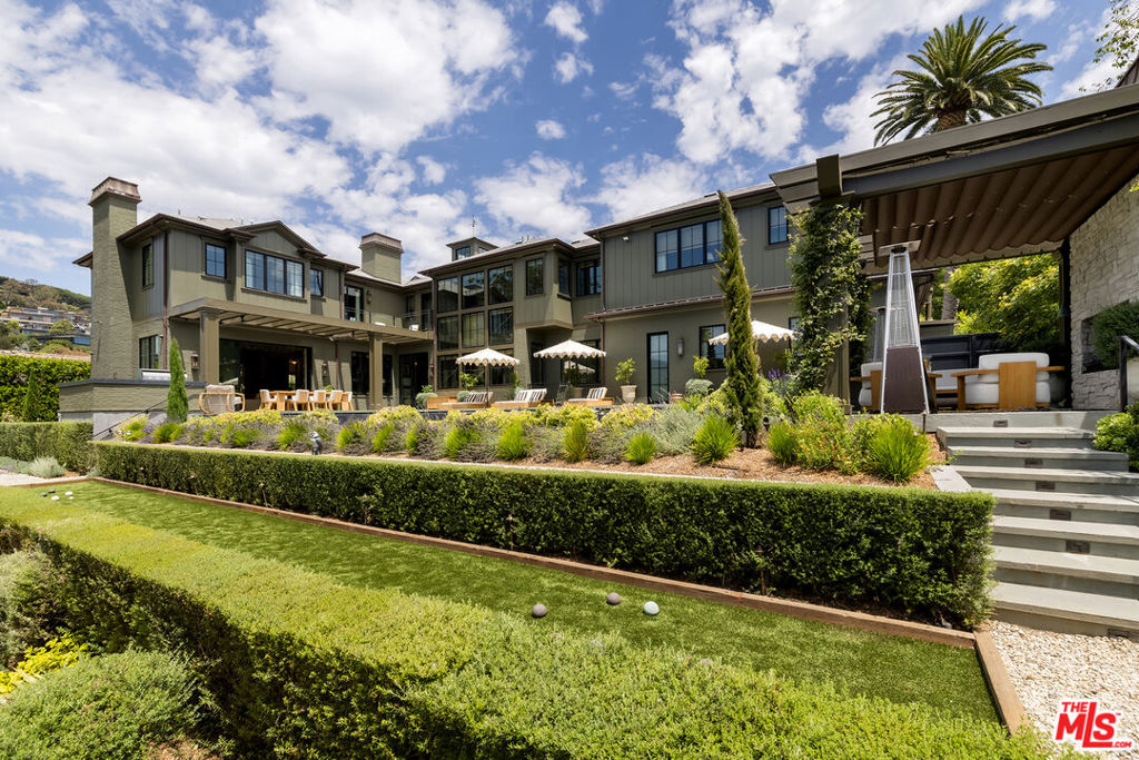 Perfectly situated in the coveted Pacific Palisades Riviera and set behind gates amidst lush and spectacular landscaping is this remarkable estate. The flawlessly executed interiors created by the renowned interior design firm Pierce and Ward, along with the home being a newly built Ken Ungar estate, make this home truly-one-of-a-kind. Every inch of the home, inside and outside, has been transformed to capture the striking canyon views and beams of light glowing through soaring windows and doors from sunrise to sunset at carefully designed vistas throughout the day. Enter through a stunning glass door to ultra-inviting living and dining rooms designed for daily enjoyment, with lavish yet welcoming interiors that appeal to all, featuring a London-chic flair mixed with mid-century design that will surely rival the best home designs executed in all of Los Angeles. The super-inviting family kitchen, with double banquet nooks you won't want to leave all day, offers counter seating, a top-of-the-line Wolf range, multiple ovens, double sinks, and wall-to-wall refrigeration, all opening to a large, stunning family room reminiscent of a chic boutique hotel. This space seamlessly transitions to a large outdoor dining table and chef's barbecue area, ideal for cooking and entertaining guests, all with stunning canyon views. The first floor also features a tucked-away office and a spacious downstairs suite, all carefully laid out with the architect's clear understanding of a masterful floor plan. The second floor boasts a primary suite tucked in its own wing, with dual doors, a fireplace, two walk-in closets: one on each end, a luxurious bath suite, for two, with an oversized double shower, soaking tub, two water closets, separate sink areas, and make-up seating for her, all with beautiful views of the meticulously landscaped grounds and a balcony completing this truly intimate and cozy suite. Across the landing, the second floor also offers a cozy upstairs family room set between three suites, each designed with extraordinary interiors and beautiful tree-top views. An elevator services all three floors, including the lower level, which features the single most inviting screening room, clearly designed for family and friends' movie nights. The lower floor also boasts a large open family room/pool and game room, a stunning bar area, and a wine room, all opening to a cozy patio with plenty of room to enjoy a cold plunge after Pilates in the custom-designed double studio suite and sauna. Down the hall, there is a jaw-dropping four-bed bunk room suite, perfect for late-night sleepovers or additional holiday guests. To complete this lush estate, there is an infinity-edge pool, oversized Baja shelves and spa, a built-in trellis with a fireplace, and a lower-level multiple seating area for guests, parties, and late-night conversations in this award-worthy landscape design encasing the entire estate. Simply exquisite and clearly one of Pierce and Ward's finest design and landscape visions.
