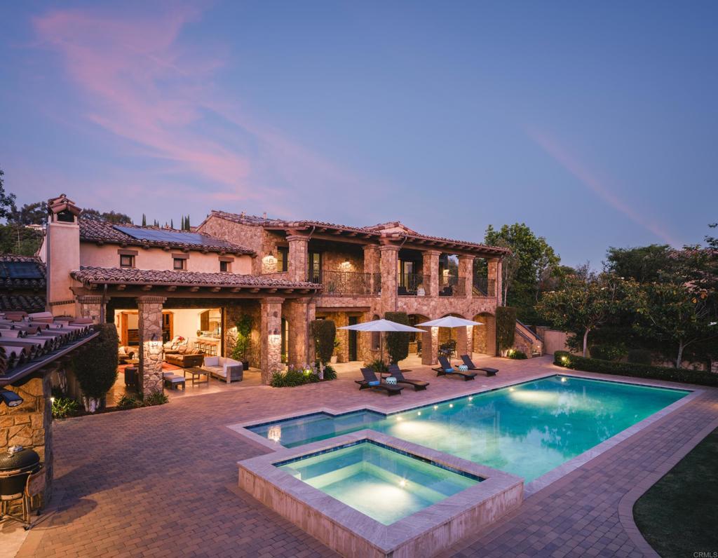 Welcome to this exceptional Henry Penner-built estate, privately gated within the prestigious Santaluz community. Thoughtfully designed for luxurious living and grand entertaining, this four-bedroom plus office residence features a seamless open floor plan and refined, timeless finishes throughout. The expansive great room flows to a built-in bar, perfect for gatherings, while the formal dining room offers an elegant space for special occasions. Movie nights transform into a cinematic experience in your private eight-seat theatre. The heart of the home is the gourmet kitchen, complete with a Wolf oven and range, Subzero refrigerator, Bosch dishwasher, and an adjacent prep kitchen-ideal for effortless hosting and everyday functionality. The main level offers two spacious bedrooms, while upstairs includes two additional bedrooms and a generous entertaining room with its own mini kitchen. Retreat to the main-level primary suite featuring a spa-like bath, outdoor spa on a private patio, and a walk-in closet with its own mini washer and dryer for added convenience. Additional highlights include a dedicated office, four-car garage, owned solar for the home and pool, and a private gated entry offering exclusivity and security. This is a rare opportunity to own a timeless Santaluz masterpiece, designed for both intimate family living and grand-scale entertaining.