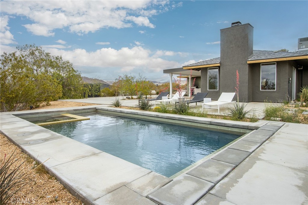 Mojave Paddle Club: Meticulously designed home & grounds featuring a custom pickleball court and in-ground pool & spa (with automatic retractable cover). The interior – thoughtfully laid out by Studio Collab Designs – features an open-concept floorplan with high-end furnishings, décor and materials sourced from renown brands such as Bedrosians, Fireclay and Zia Tiles. Turnkey/Fully furnished interior - including a custom Interior Define sofa, a dining room table from Burke Decor & another dining room table from Inside Weather, in addition to high quality Tuft & Needle mattresses, Floyd Bedframes to name a few. Pet friendly fully-fenced backyard. Mojave Paddle Club has been featured in Palm Springs Life Magazine. Currently used as a vacation getaway and vacation rental, this spacious home comfortably sleeps up to eight guests in three rooms. The kitchen, dining and living area compose one wing of the house with a third room set up to be utilized as an office, game room, or additional bedroom. Primary bedrooms are located at the opposite end to allow for privacy and sleeping while other stay up socializing. The primary bedrooms showcase exquisitely tiled bathrooms and private access to the court and pool. Back out in the living area, relax by the wood burning fireplace or retreat to the yoga room out back. The expansive kitchen area is fully equipped and offers views of the outdoor patio, pool, and pickleball courts. A table for six in front of the fireplace provides an ideal space for formal dining or casual gatherings. Or enjoy meals al fresco near the propane BBQ and outdoor dining area. Fully remodeled and updated inside and out, new surfaces everywhere and new systems, including an efficient central HVAC. Smartly landscape with drought resistant vegetation. Dark nights perfect for stargazing from the spa. Minutes to the downtown Farmers Market or the front gate to Joshua Tree National Park just up the road. Come visit this exquisite resort-like ambiance today. STR earned over $100k in 2024.