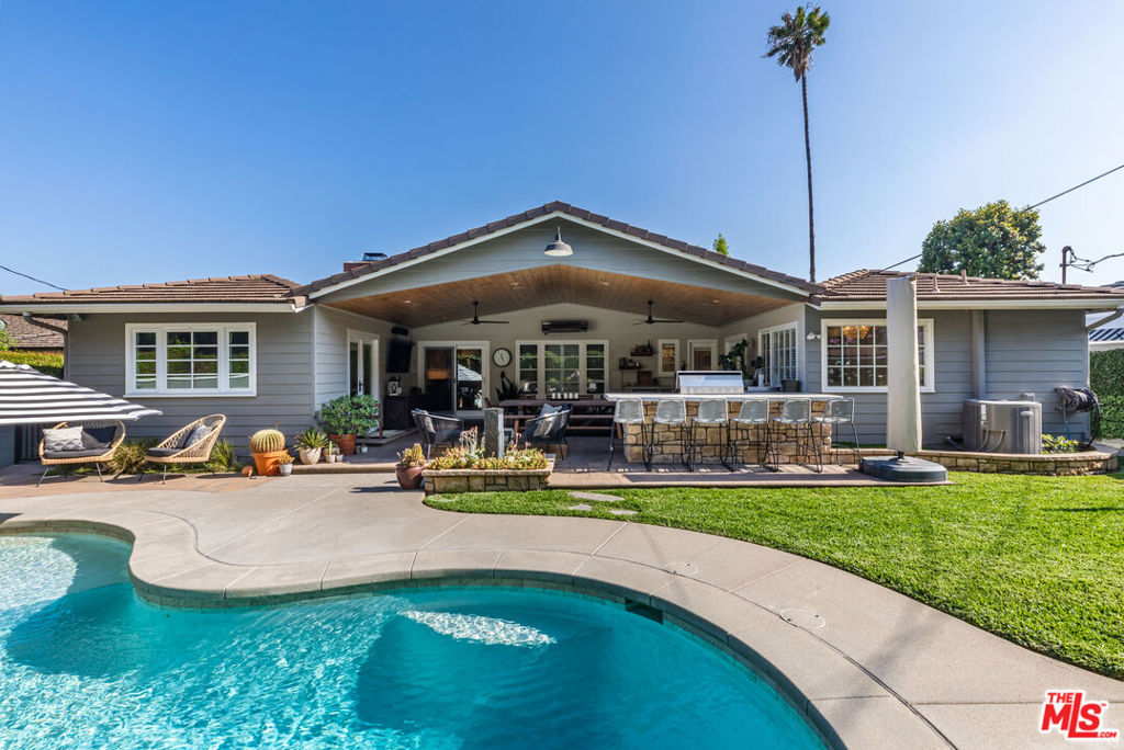 Located in one of Arcadia's most desirable neighborhoods, this beautifully updated single-level home blends timeless charm with resort-style outdoor living. Nestled on a tree-lined street in the heart of the prestigious Hugo Reid community, this property offers both privacy and proximity to award-winning schools, parks, and backs up to the Arboretum. Step inside to discover a light-filled interior featuring an elegant living room with a classic fireplace, crown molding, and views of the manicured front yard. The bright, modern kitchen is the heart of the home - complete with a spacious island, new stainless steel appliances, and abundant cabinetry, perfect for both everyday living and entertaining. Out back is where this home truly shines. Enjoy a custom-designed pool with a baja shelf and integrated spa, surrounded by lush landscaping and tall privacy hedges. The expansive covered patio is an entertainer's dream, boasting a full outdoor kitchen with built-in BBQ, bar seating, a dining area, outdoor heaters, ceiling fans, and a mounted TV - ideal for year-round gatherings. Additional features include a bonus/office room, a lush, beautifully maintained lot with mature trees and vibrant landscaping, exceptional curb appeal with a wide driveway and attached two-car garage, and a location that puts you just minutes from Westfield Santa Anita, the Los Angeles County Arboretum, Santa Anita Golf Course, and the highly acclaimed Hugo Reid Elementary School. Whether you're looking for your forever home or the ultimate entertainer's haven, 875 Hugo Reid Drive delivers unmatched comfort, style, and location.