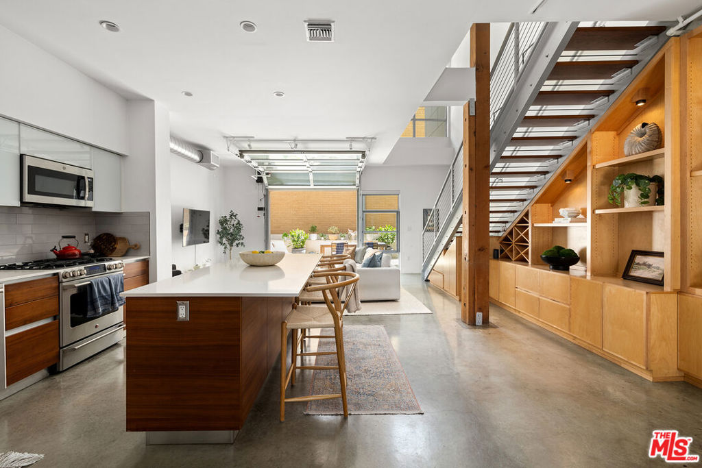 Sleek, sophisticated, and architecturally stunning, this rare end unit at T-Lofts offers the ultimate in modern Westside LA living. Soaring ceilings, expansive windows, and polished concrete and hardwood floors set the tone for this bright, two-story residence, thoughtfully designed for both form and function. With two spacious bedrooms, three full bathrooms, and a flexible bonus den perfect for a home office or creative space, the open-concept layout flows seamlessly from the chef's kitchen to the oversized private patio via an industrial-style automated roll-up door ideal for indoor-outdoor living and entertaining. Designer finishes throughout, numerous upgrades, custom built-ins, and contemporary touches abound, including Caesarstone counters, stainless steel appliances, reverse osmosis water purification, recessed lighting, and a luxurious primary suite with a spa-like bathroom and walk-in closet. Set within a secured, beautifully landscaped, eco-conscious community in the heart of Sawtelle, residents enjoy resort-style amenities including hot tub and outdoor shower, BBQ area, fitness center, package lockers, multiple outdoor seating areas and unbeatable access to LA's best dining, shops, and coastal conveniences. Two side by side parking spaces next to the elevator, 35 guest spaces, electric car charging and bike racks. Welcome to West LA loft living at its finest.