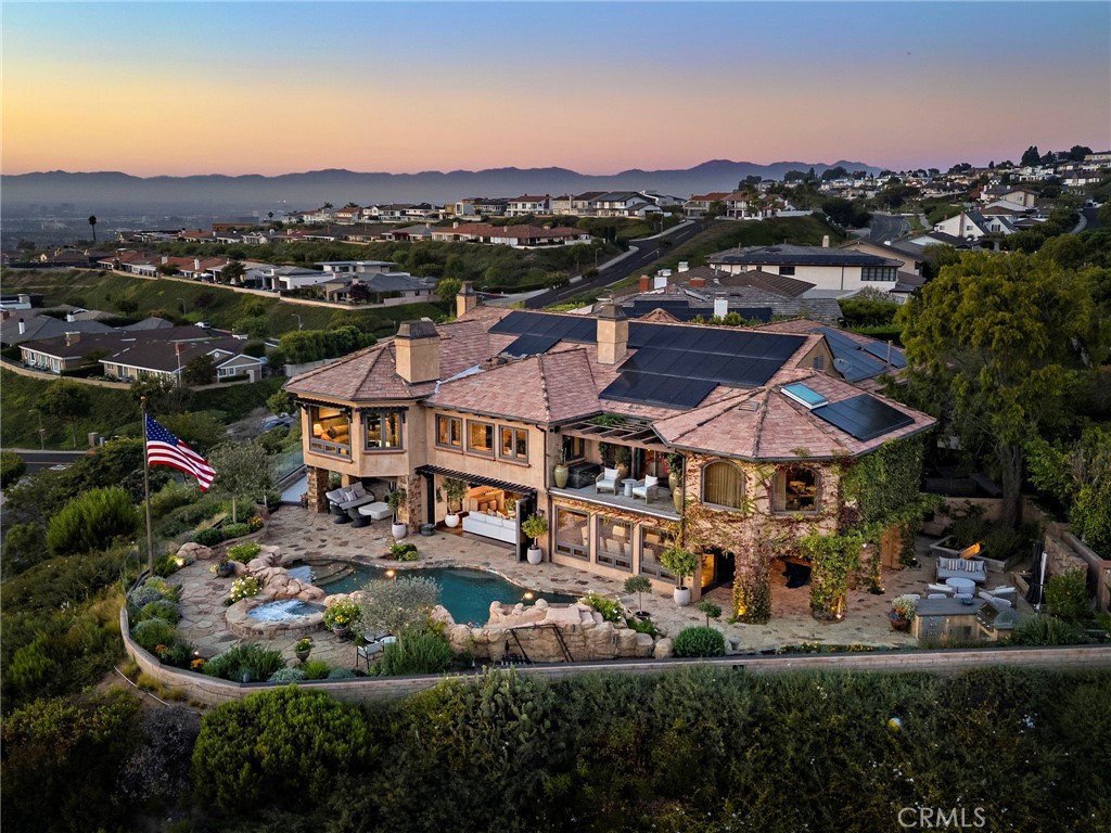 Available for the first time in nearly two decades, 25 San Mateo Way is one of the most iconic offerings in Corona del Mar’s Spyglass Hill. Set on an extraordinary oversized lot with rare positioning, this trophy estate captures sweeping, unobstructed views that span Newport Coast’s hillsides, Pelican Hill Golf Course, the Pacific Ocean, Catalina Island, Newport Harbor, Fashion Island, and sparkling city lights stretching to downtown LA. A private gated driveway leads to the residence, where approximately 7,109 sqft of interior living space is complemented by nearly 720 sqft of covered outdoor loggia space. Nearly every room in the home embraces the panoramic vistas and unparalleled privacy. The main level begins with a grand foyer and features a formal living room, wine room & tasting area, sunroom retreat, and an expansive great room that blends the family room, kitchen, and informal dining for 10+. Frameless glass bi-fold doors extend the interiors to the backyard sanctuary. A main-level ensuite bedroom offers comfort for guests. The upper level hosts 4 additional bedrooms, including an executive office with retreat and a large loft/media room. In total, the home offers 5 bedrooms plus office, bonus room, optional gym or private den, multiple living areas, and exceptional flexibility. Resort-like grounds create a setting designed for both entertainment and everyday enjoyment. Highlights include a pool with slide, spa, waterfalls, built-in BBQ island, crushed seashell bocce ball court, water features, and two covered loggia spaces: one designed for dining al fresco, the other for lounging with a fireplace and television. The meticulously maintained landscaping evokes the romance of Tuscany and offers multiple seating points to enjoy the endless views. With its gated entry, oversized driveway, 3-car garage, and unique setback that ensures unusual privacy, 25 San Mateo Way stands apart as a truly one-of-a-kind opportunity. Combining iconic views, timeless design, and a legacy lot, this estate represents the very best of coastal Orange County living - just a stone’s throw from premier shopping and dining at Fashion Island and the CdM Village, five-star luxury resorts, award-winning schools, John Wayne Airport, and convenient freeway access.