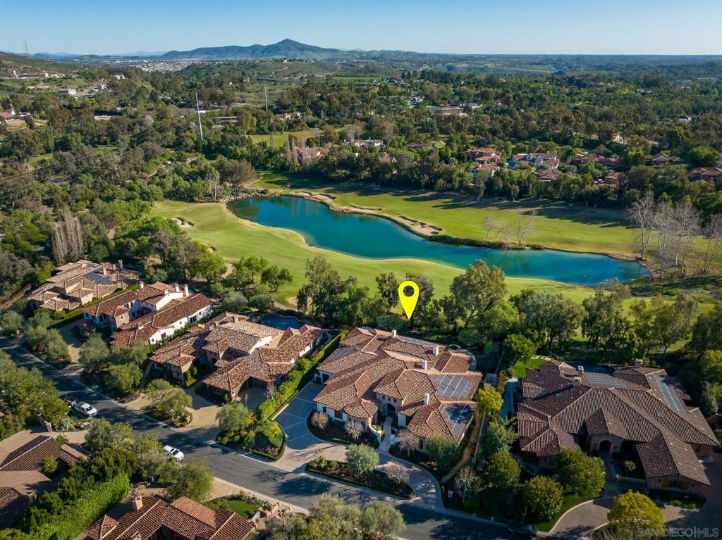 Located above the 6th Fairway, offering breathtaking views of the lake and 5th fairway in the exclusive golf course community at Bridges of Rancho Santa Fe. Step into this recently updated, custom single-level masterpiece, meticulously designed with exceptional quality and attention to detail. The high voluminous ceilings and wide hallways bathe every corner in an abundance of natural light. As you enter through the center courtyard with a soothing free-form water feature. Large pocket doors effortlessly open to reveal mesmerizing views of the lake and golf course, creating an unparalleled indoor-outdoor experience. Entertain with ease in the spacious living areas featuring vaulted beam ceilings, while the gourmet chef's kitchen, complete with two islands and custom built-ins, surrounds you with the stunning backdrop of the golf course. For the car enthusiast, there's a three-car garage plus a separate golf cart garage with direct access to the kitchen, making life even more convenient. Retreat to the primary suite, where a spa-like bathroom awaits, complete with two separate clothes closets. One of these closets is exceptionally oversized and boasts its own private desk area for your convenience. Two additional bedroom suites, each with en-suite bathrooms, provide ample space and comfort for family and guests. Find solace in the separate TV retreat, adorned with wood paneling and a cozy fireplace, making it the perfect spot to unwind.