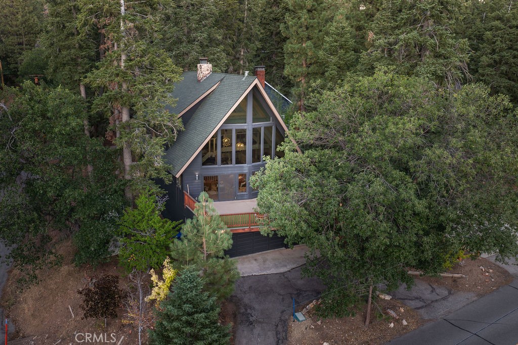 Welcome to Oak & Luna, the A-Frame of Your Dreams! Nestled amongst the majestic pines and oaks of desirable Moonridge, this completely updated and upgraded 4-bedroom, 3.5-bath mountain chalet is the epitome of modern mountain living. Situated on a coveted corner lot with unobstructed open treed views across the street, this gorgeous retreat offers both privacy and tranquility. From the moment you step inside, you’ll be wowed by the thoughtful design touches that make this home truly special. Soaring vaulted ceilings, expansive dual-pane windows, and a stunning dual-sided fireplace that connects the living room and kitchen set the stage for relaxation and entertainment. This home has been meticulously renovated, with attention to every detail. The newly added movie room and redesigned family-style loft bedroom, now sleeping five, offer even more space for family and friends. This is the perfect space for full-time living or an ideal vacation home. Enjoy the added benefit of low-maintenance vinyl siding, a recently refinished wrap-around deck, and an attached 720 SF garage with laundry and generous storage. Whether you’re relaxing on the deck, warming up by the fire, or enjoying the immediate area by spending a day at Bear Mountain on the slopes, the Golf Course or the Zoo, this A-frame is very unique and just what you’ve been waiting for.