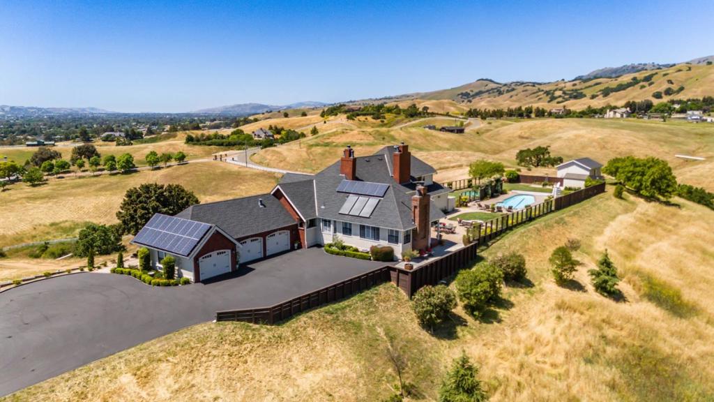 Perched atop 10.7 private acres with sweeping 360º views, this 5-bed, 4.5-bath hilltop estate offers 4,207 sq.ft. of refined living space & a rare combination of privacy, natural beauty, & convenience. The kitchen pairs maple cabinetry with granite counters, a large island with prep sink, & high-end appliances including a Wolf 5-burner cooktop, Thermador double oven, Sub-Zero refrigerator, Miele dishwasher, & built-in warming drawer. A formal dining room seats 12, while multiple living areas provide inviting spaces to relax & entertain. The primary suite features a fireplace lounge, vaulted ceilings, a jetted soaking tub, dual vanities, & a walk-in closet. All bedrooms offer hillside or valley views, with one used as a dedicated office boasting a south-facing window that frames stunning sunsets over Gilroy Valley. Once outdoors enjoy the pool, fire pit, grassy lawn, & stone patio all set against open skies & quiet stillness. Skillet Creek runs through the property, & in winter its gentle, winding flow adds a soft, lyrical soundtrack to the landscape. Minutes to Gilroy Outlets, golf, dining, & Harvey Bear/Coyote Lake parks, with farmers markets, the Wine Trail, & essentials like Costco, Home Depot, & local restaurants this home is the ideal balance of retreat & convenience.