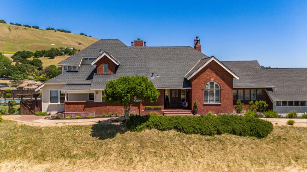 Perched atop 10.7 private acres with 360º views, this 5-bed, 4.5-bath hilltop estate offers 4,207 sq.ft. of refined living space and a rare blend of privacy, natural beauty, and convenience. The kitchen features granite counters, maple cabinetry, a large island with prep sink, and high-end appliances including a Wolf 5-burner cooktop, Thermador double oven, Sub-Zero fridge, Miele dishwasher, and built-in warming drawer. A formal dining room seats 10, and multiple living areas offer space to relax and entertain. The primary suite includes a fireplace lounge, vaulted ceilings, a jetted soaking tub, dual vanities, and a walk-in closet. All bedrooms enjoy hillside or valley views, with one thoughtfully designed as an office featuring a south-facing window that captures stunning sunsets and expansive views of the Gilroy Valley. Outside, enjoy a pool, fire pit, grassy yard, and stone patio all framed by sunset skies and peaceful stillness. Minutes to Gilroy Outlets, wineries, golf, dining, and Harvey Bear/Coyote Lake parks. Local farmers markets, the Wine Trail, and daily essentials like Costco, Home Depot, and restaurants are all nearby offering the perfect balance of retreat and convenience.