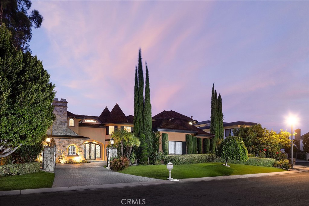 This exceptional, custom Nellie Gail Ranch view home offers true resort-style living with sweeping mountain, canyon and city light views from nearly half an acre of private, equestrian-zoned grounds. Upon arrival, stately entry gates open to a brick motorcourt and generous three-car garage. Ornate, oversized double entry doors reveal an interior of dramatic scale and proportion, spanning over 5,800 square feet. The foyer features floor-to-ceiling windows, filling the space with natural light, and a sweeping wrought-iron staircase leads to private quarters above. The grand formal dining room is ready for gatherings, while the living room features a contemporary fireplace and marble wet bar with wine storage, all complemented by priceless views. A second dining area flows seamlessly into the gourmet chef's kitchen, equipped with Viking appliances, abundant quartz counters, upgraded cabinetry and walk-in pantry. The large center quartz island with cooktop and breakfast bar seating invites casual meals and conversation. Neighboring the kitchen, you will find the well-equipped laundry room with upgraded LG front-loaders, additional sink and storage, and direct exterior door. The main level also includes a versatile office or home theatre/bonus room with blackout shades, fireplace, extensive built-ins and adjacent ½ bath. The primary suite serves as a private retreat with its own sitting room, fireplace, and stunning views. Outside, a terraced patio hardscape with multiple sundecks surrounds the inviting pool and spa, all overlooking endless views and shrouded in mature landscaping for ultimate privacy. Expansive Trex decking features a covered, fully equipped outdoor kitchen and bar, an entertainer’s dream. The lower deck area includes a gazebo lounge and TV area. Additional upgrades include full Pex repipe, Eagle-light roofing system and upgraded windows and doors. Nellie Gail Ranch offers exceptional value with low HOA fees covering security, trail maintenance, access to the swim, tennis and pickleball club and exclusive community events. With easy access to freeways, top schooling, shopping, dining, and world-class beaches, this special property provides the perfect blend of amenities, privacy and location. Truly a must see! Shown by private appointment only.