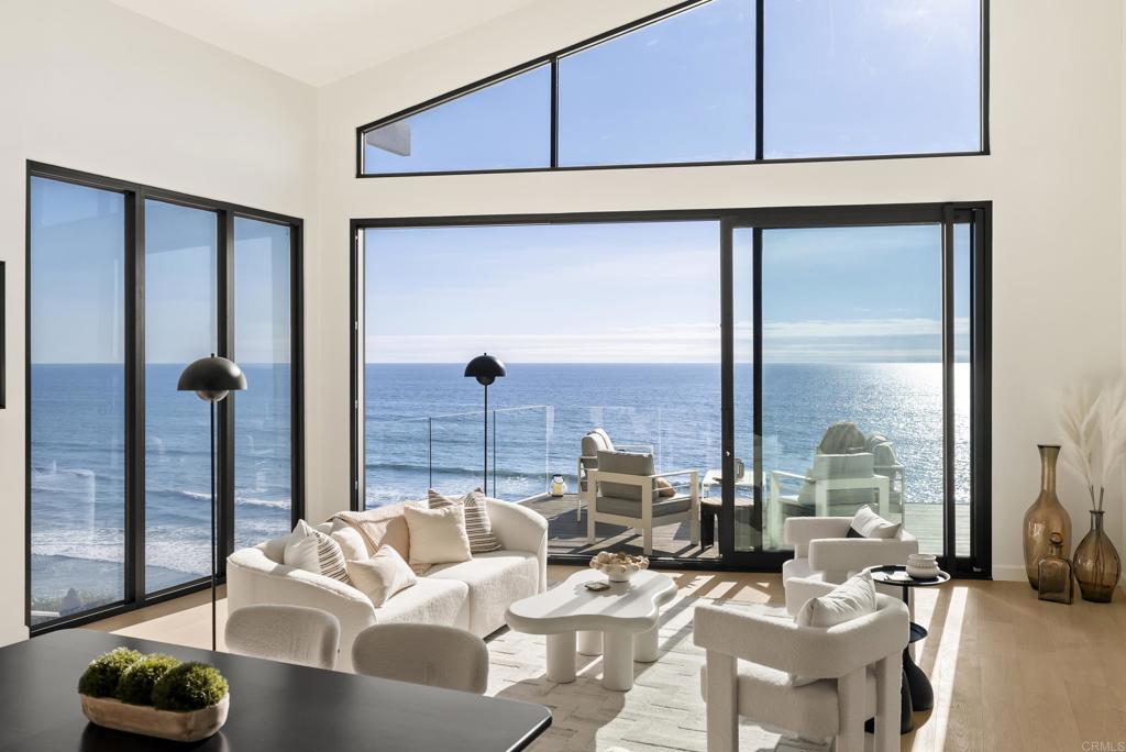 Experience oceanfront luxury at 1006 Neptune Avenue, a fully reimagined coastal masterpiece perched atop the bluff in Encinitas. Just steps from Beacons Beach, this stunning home offers effortless access to the sand, surf, and sun, making it a true sanctuary for beach lovers and those seeking the ultimate California lifestyle. Boasting three bedrooms plus a loft and four full bathrooms, this exquisitely remodeled residence showcases custom finishes by a premier luxury design-build team. Engineered hardwood floors flow throughout the home, complementing the sophisticated design and seamless indoor-outdoor living. Oversized, made-to-order aluminum sliding doors on both levels frame breathtaking ocean views, while two custom smart windows allow for instant privacy with the touch of a button. The primary suite is a private oasis, featuring floating custom mirrors over a double vanity, a spa-like soaking tub, a rain shower, and a walk-in closet—all positioned to maximize the endless ocean vistas. A second primary suite upstairs offers an ensuite retreat with a custom double vanity and an oversized soaking tub with shower. Each bathroom throughout the home is adorned with designer lighting, push-to-open custom vanities, and luxury tile, including fluted marble accents in the kitchen.