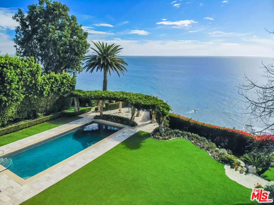 Magnificent ocean view compound with a prestigious PCH address. Behind impressive gates are privacy hedges, sculptured garden, elegant two bedroom guest house, beautiful two story structure with two offices, guest suite and lighted tennis court. A long driveway leads to a dramatic main residence with high arches and barreled and coffered ceilings. The formal living room flows through windowed doors to a stone patio with fireplace, pool and spa, dining and lounging areas, barbecue, bar, expansive lawn and trellised sitting area overlooking the Pacific. The views throughout the day are culminated by watching the setting sun. Entertain in the stately dining room adjacent to a chef's kitchen with large island and butler's pantry that leads to a media area and dining banquette. The stunning ocean view master suite shines with his and her baths and large walk-in closets. Additional amenities include an ocean view executive office, exercise room, guest suite, custom tiled laundry room and three car garage on this magnificently manicured property. An additional parcel fronting Malibu Road known as APN: 4458-015-040 is included in the sale making the total property size approximately 1.55 acres. This spectacular coastal estate is truly one of Malibu's most coveted properties.