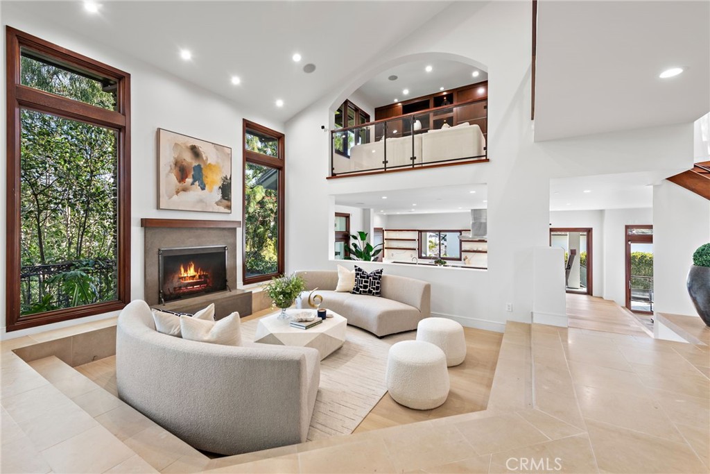 Nestled on a coveted corner lot, this exceptional estate sits beside Cliff Drive Park on one side and just steps away from a lush greenbelt on the other, creating a unique blend of privacy, beauty, and convenience. With sweeping views of the ocean, harbor, and Catalina Island, this property is a true masterpiece of coastal living. Spanning over 5,000 square feet, this five-bedroom (optional sixth) home, with five-and-a-half baths, offers a seamless fusion of luxury, design, and natural surroundings. The entry is framed by a serene walkway with water features leading to double doors. Inside, the open foyer with soaring ceilings, a central fireplace, and expansive Marvin windows create a bright, welcoming atmosphere. Wood and stone flooring and custom millwork add a refined touch, while sunken common areas enhance the sense of space. On the main level, you'll find two spacious en suite bedrooms, a formal living room, a wine room, and an open-concept dining area that flows into a gourmet kitchen and family room. The kitchen features Thermador appliances, a 13-foot "Bistro"-style island, quartz countertops, and custom cabinetry. Glass doors open to a covered terrace, offering sweeping harbor views. The private wing is home to the primary suite, which includes a fireplace, private balcony, a large walk-in closet, and a spa-like bath. On the same level, a media room, library, office, two additional en suite bedrooms with built-in study areas, and an upstairs family room complete the living spaces. Outside, the backyard is an entertainer’s dream, featuring a saltwater pool, built-in BBQ, and plenty of space for al fresco dining, all framed by breathtaking coastal views. Other highlights include a Vantage lighting system, a laundry room, and a sweeping driveway leading to a three-car garage, all set amidst beautifully manicured landscaping. Located just minutes from shopping, dining, and the Balboa Peninsula, this home offers the perfect combination of privacy, luxury, and convenience.