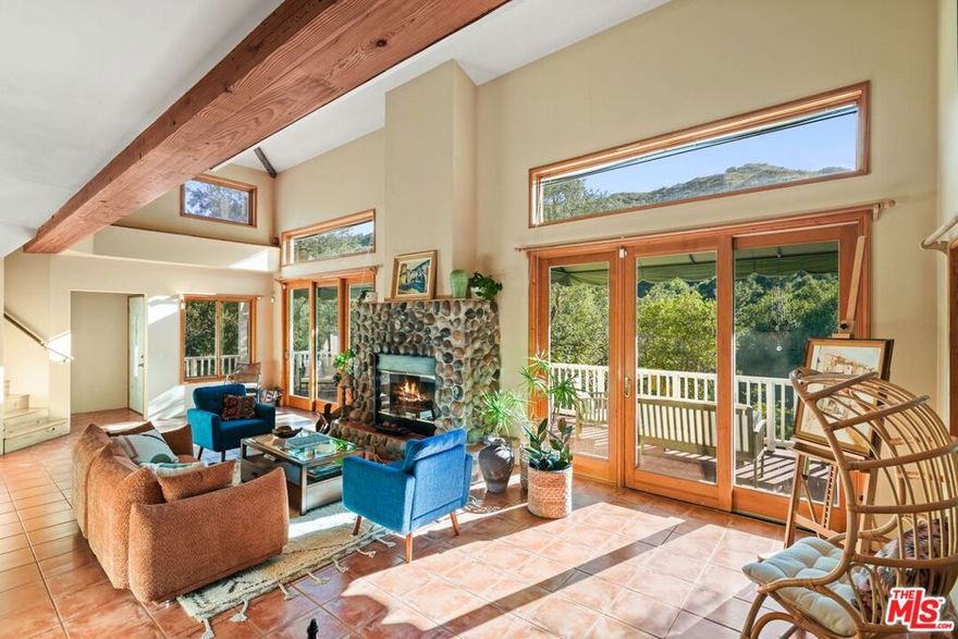 Casa Cielo: A Stunning Retreat & Rare Approved Coastal Development Permit for Second Home in Topanga Canyon. Tucked into the gentle folds of Old Topanga Canyon, where the hills rise softly into the sky and ancient oaks sway in rhythm with the breeze, Casa Cielo is more than a home, it is a canyon dream, rooted in beauty, vision, and possibility. Up a long driveway, spread across nearly three private acres on two separate legal parcels, this modern Mediterranean sanctuary offers both an exquisite residence and an extraordinary development opportunity, moments from Malibu, Calabasas, and the Pacific. Your paradise on a hill, with views all around, custom built in 2002, rests on just under two-thirds of an acre, an elegant expression of warmth and architectural grace. Light pours through French doors and skylights onto pine and ceramic tile floors, while a two-story stone fireplace warms the voluminous great room. A generous chef's kitchen, with unique Picasso Green Granite countertops, walk-in pantry, and stainless appliances, opens seamlessly to an entertainer's patio, where a built-in BBQ awaits long summer evenings under canyon skies. A burbling fountain and birdsong are the music to morning coffee, or to a gathering of loved ones on the flower-framed back patio. Upstairs, two airy bedrooms share a dreamy, French inspired, Jack-and-Jill bath adorned with a clawfoot tub and antique vanities. The primary suite opens to a private balcony with panoramic views, while an open loft with built-in shelving offers the perfect nook for a library, art studio, or meditation space. Downstairs, a spacious convertible den, with its own full bath and balcony, can easily serve as a third bedroom, office, or guest retreat. Panoramic views entice from a spacious upper deck, with covered side porch, and from a lower covered patio set in the garden. Thoughtfully appointed with central HVAC, a gray water recycling system, an automatic interior sprinkler system for enhanced safety and peace of mind, and a laundry chute to a generous laundry room, Casa Cielo blends timeless aesthetics with everyday comfort. The 2 car garage has a workshop area, and has cable hookups, in case one needs a hideaway more than parking for a second car! At the bottom of the driveway, a charming cottage studio, in a private yard, invites creativity, solitude, or guests. But the true rarity lies just beyond: over a small footbridge, the second parcel, encompassing 2.33 sunlit, view acres of pristine canyon land, you'll find a refined and ready canvas for new architecture and legacy building. Unlike raw, speculative land, this property is fully vested and entitled under a Coastal Development Permit for a custom single-family residence. Utilities are already in place, with a temporary power meter and water meter installed, removing costly delays and allowing your vision to unfold without hesitation. Already graded, and with driveway access, this lot is your opportunity to create an incredible compound, with room for anything your heart desires! Gardens, orchards, horse facilities, a hobby farm, and possibly a pool. What makes this offering even more remarkable is the land's architectural pedigree. The plans were drawn by John Geiger, a celebrated architect and former member of the Taliesin Fellowship under Frank Lloyd Wright. His vision, rooted in the principles of organic architecture and attuned to the undulating canyon topography, lives on in the possibility this land holds, a legacy not only of shelter but of soul. Here, in one of Southern California's most protected and poetic enclaves, you're invited to dwell, dream, and design. Whether you embrace the sanctuary of Casa Cielo as it stands, or choose to expand the story with a second architectural jewel, this is a place where vision meets readiness, where artistry meets the earth, and where time slows to the rhythm of the canyon.