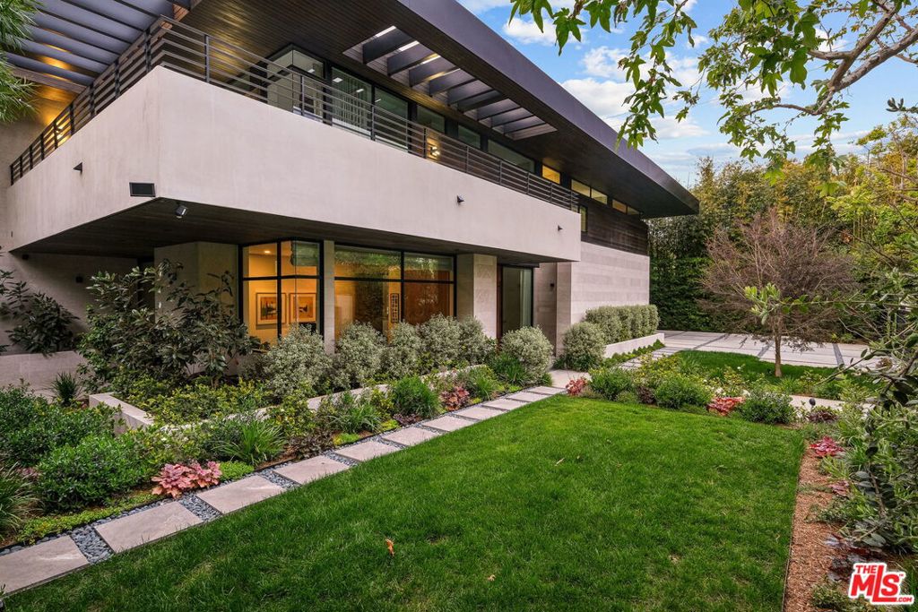 Set within a highly convenient Brentwood locale just moments from the coveted shopping and dining of San Vicente, this Michael Lee-designed modern masterpiece combines the best in sophisticated California living and naturally inspired comforts. Awash in natural light via large windows and skylights, the two-story foyer flows seamlessly into an office with inspirational views, dining room, full bar and dual living areas separated by a freestanding travertine fireplace. The state-of-the-art chef's kitchen is equipped with Miele appliances and a large butler's pantry. This open-concept main level is enveloped by floor-to-ceiling glass sliding doors that open to the home's zen-like outdoor space, complete with multiple lounge areas, built-in BBQ and sparkling pool and spa, all embraced by tall hedges for total serenity. Via a floating staircase, find four en suite bedrooms, including the luxe primary suite with an immense closet, astounding spa bath with dual shower, soaking tub and its own balcony amid the treetops. On the home's lower level, discover a large living space, temperature-controlled wine room, full bath, guest quarters with en suite, gym, and spacious home theater all with direct access to the backyard. A true architectural feat, this home sets a new standard for modern living on one of Brentwood's most sought-after streets.