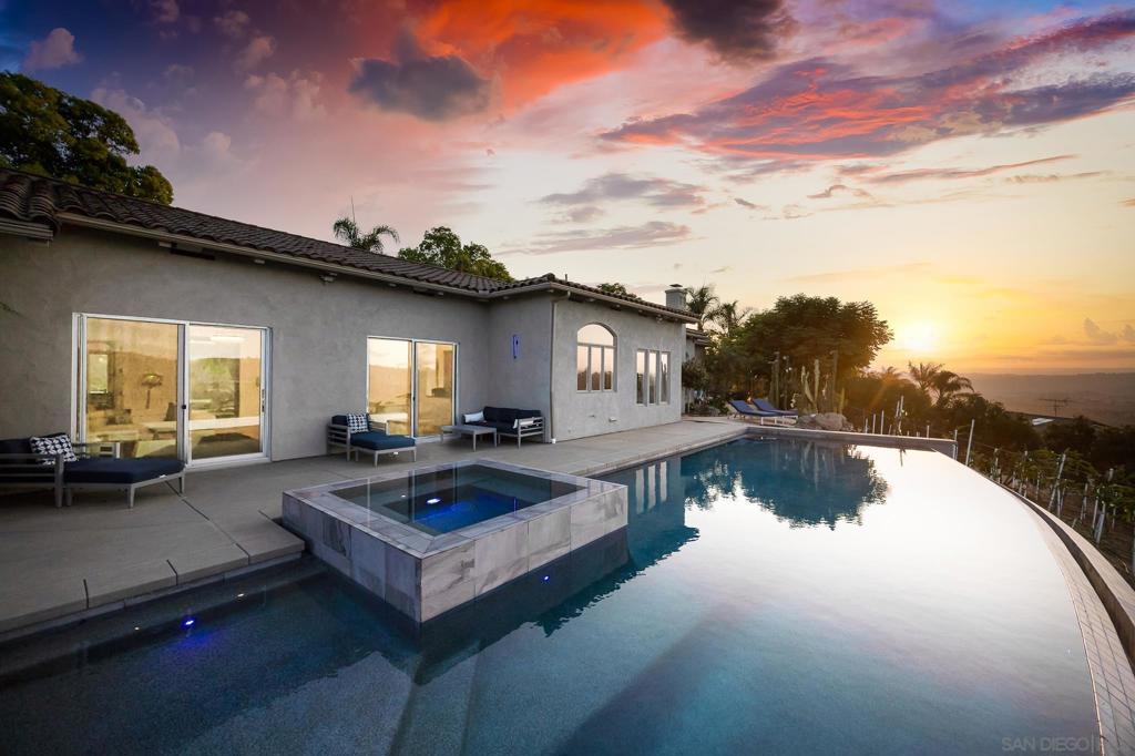 “Come for the view, stay for the home.” Welcome to “Tuscan Sun”, a breathtaking single-story Mediterranean-style retreat of over 4,000 sq ft, perched atop rolling hills with panoramic views stretching endlessly from east to west. This completely remodeled custom home sits on 4.4 fully maintained acres with 400+ thriving dragon fruit trees, efficient drip irrigation, manicured pathways, and a rock garden whimsically named “Stonehenge.” Inside, natural light floods soaring ceilings through new Fleetwood sliding and trifold doors. Elegant shutters, new fixtures, and designer hardware add sophistication. The chef’s kitchen features sleek black granite counters, new Café appliances, custom soft- close cabinetry, and a spacious island perfect for gatherings. The east wing hosts a luxurious primary suite with spa-inspired bath, soaking tub, oversized rainfall shower, dual vanities, and reimagined walk-in closet. The west wing offers two remodeled bedrooms with en-suite baths and custom closets, a bonus gym room, and a newly renovated home office with inspiring views. Enjoy the resort-style patio with a brand-new, breathtaking 40-ft saltwater infinity pool and spa, outdoor speakers, and expansive pool deck ideal for unforgettable sunsets. Upgrades include epoxied 3-car garage floors, dual water heaters, a whole-house generator, upgraded dual-zone HVAC, and restored gas fireplaces. This is more than a home—it’s a sanctuary of luxury, privacy, and Southern California beauty. “Come for the view, stay for the home.”