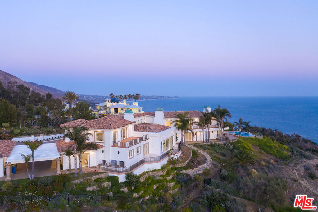 Harmony, grace, and unrivaled ocean and island views define this inspired Mediterranean villa created for grand indoor-outdoor entertaining. Set behind gates on more than five acres, the property is superbly crafted and gorgeously appointed inside and out. Complete with a guest house and dual owner's suites, the residence combines traditional details, such as vaulted ceilings, soffit lighting, and travertine floors, with an updated open layout, elevator, built-in sound system, and expansive use of glass. The property is fully permitted and ready to build a tennis court. The grand chandelier foyer reveals the home's sophisticated elegance, with panoramic ocean views that are enjoyed by almost every room. Step down to the majestic living room, complete with a huge fireplace and extra-wide glass doors that open to a wraparound view balcony. The adjacent dining room shares the balcony and ocean views, while the spacious family room has French doors onto the front yard. The enormous kitchen would impress any chef, with dark green granite countertops, a large island with seating and built-ins, dual appliances of exceptional quality, and a pantry room.A hallway off the kitchen has a full bath as well as an en-suite bedroom with ocean views. From the foyer, the home's other wing features an ocean-view office, a two-tiered movie theater, and three more en-suite bedrooms. A laundry room and two powder rooms complete the main floor. The upper level, accessed by elevator or the wide central staircase, comprises two exquisite ocean-view owner's suites, each with vaulted ceilings, hand-scraped walnut floors, fireplace, sitting area, balcony, huge custom closets, and a total of three lavish spa-style bathrooms. The estate's manicured grounds with a new sprinkler system, mature trees, and fruit orchards feature an ocean-view infinity pool and spa, generous patio space for dining and entertaining, and an outdoor kitchen, and seating area. A separate one-bedroom, one-bath guest house is near the home's entry and the three-car garage. There is additional parking for more than a dozen cars. This is a legacy estate of spectacular character and quality. All the A/C units in the main house are new. The home music system and speakers are new. The appraised House SF is 10,689, the Guest House SF is 312.