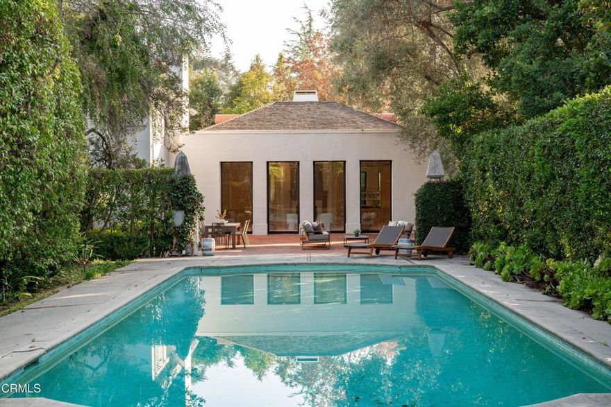 Secluded beyond lush hedges and a private gate, this distinguished 1923 estate by celebrated and important architect Reginald Johnson embodies timeless elegance and is located on a full level acre just north of The Huntington Library. Spanning over 5,000 square feet, the home's gracious interiors begin with a wood-paneled central hall which opens up to a light-filled living room with three French doors, an elegant dining room and a chef's kitchen with generous island, butler's pantry, and breakfast nook. Its grand staircase leads to two of three spacious guest suites and the primary retreat offering abundant closets and a marble-clad bath. The already stately colonial revival style home transcended its own stature with a massive neomodernist Main Room addition in 1991 with a commanding presence that sets up long views up and down the giant herringbone brick patio, sparkling pool and landscaped gardens, serving as a library, art gallery and/or primary indoor/outdoor entertainment area. A lighted championship north-south tennis court with gazebo, multiple patios and an orchard allows for refined entertaining and expansive play. Fenced and hidden from the street by dense greenery, the estate affords both total privacy and the capacity to be an alluring social hub. Down the street from Caltech and South Lake Avenue with easy access to Greater Los Angeles, this complete property is absolutely one of a kind and on the market for the first time in nearly half a century.