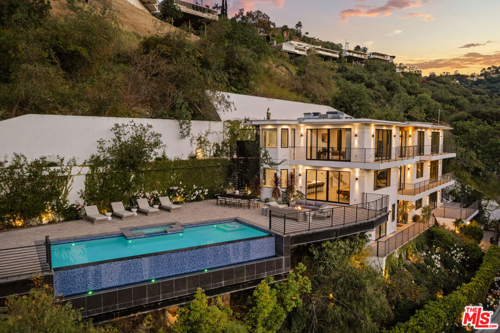 Experience unparalleled luxury at 3820 Knobhill Drive, a stunning modern estate perched in the hills of Sherman Oaks. Built in 2020, this four-story architectural masterpiece offers over 6,300 square feet of meticulously designed living space, seamlessly blending cutting-edge design with refined comfort. As you step inside, you're greeted by expansive open-concept interiors, soaring ceilings, and panoramic views stretching from the mountains to the city lights.The gourmet kitchen is a chef's dream, featuring custom cabinetry, an oversized island, and premium appliances, ideal for both intimate dinners and grand-scale entertaining. The spacious primary suite is a true retreat, complete with a spa-like bathroom, walk-in closet, and private balcony to enjoy sweeping valley vistas. A state-of-the-art home theater, an industrial-grade gym, and a collector's 10-car garage elevate this home to a class of its own. The property also features a fully installed Control4 home automation system and a state-of-the-art AI-powered home security system with 4K cameras and remote mobile app access, ensuring comfort, convenience, and peace of mind. Outdoors, enjoy a resort-style setting with an infinity-edge pool and spa, lounge areas, a natural gas fire pit, and dramatic sunset views. Privacy and security are paramount with a gated entrance and comprehensive surveillance system. Perfectly located minutes from Ventura Boulevard yet tucked away for tranquility, this is the ultimate Southern California lifestyle statement. Welcome to modern luxury redefined.