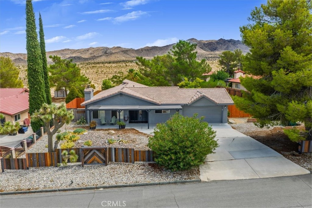 Live Auction! Bidding to start from $400,000! Welcome to your desert retreat! This spacious 3-bedroom, 2-bath ranch-style home offers approximately 1,849 sq. ft. of living space on nearly half an acre, perfectly blending privacy, comfort, and natural beauty. Located in one of Yucca Valley’s most desirable neighborhoods, the property backs up to open desert landscape, offering endless mountain and panoramic views that capture the essence of high-desert living. Inside, you’ll find a warm and inviting living room with a classic stone fireplace, perfect for gathering on cool desert evenings. An additional family room and a sunlit patio room create flexible spaces for entertaining, hobbies, or simply relaxing. The primary suite is a true retreat, boasting soaring ceilings, a spa-inspired bathroom with walk-in tiled shower, and private outdoor access for enjoying morning coffee or nighttime stargazing. The thoughtful floor plan continues with two additional bedrooms, a well-appointed hall bath, and ample storage throughout. Other highlights include white wood shutters, carpeted flooring, natural gas service, and an attached 2-car garage for convenience. Step outside to enjoy the expansive backyard, accented by mature pine trees, desert landscaping, and a private patio area ideal for barbecues, gatherings, or quiet evenings under the stars. The property’s generous lot provides plenty of room for personalization—add a pool, garden, or outdoor lounge to make it your own desert oasis. Located just minutes from Joshua Tree National Park, shopping, dining, and schools, this home offers the perfect combination of seclusion and accessibility. Whether you’re looking for a primary residence, weekend getaway, or investment property, 8799 Palomar Ave delivers the quintessential high-desert lifestyle with space, comfort, and character.