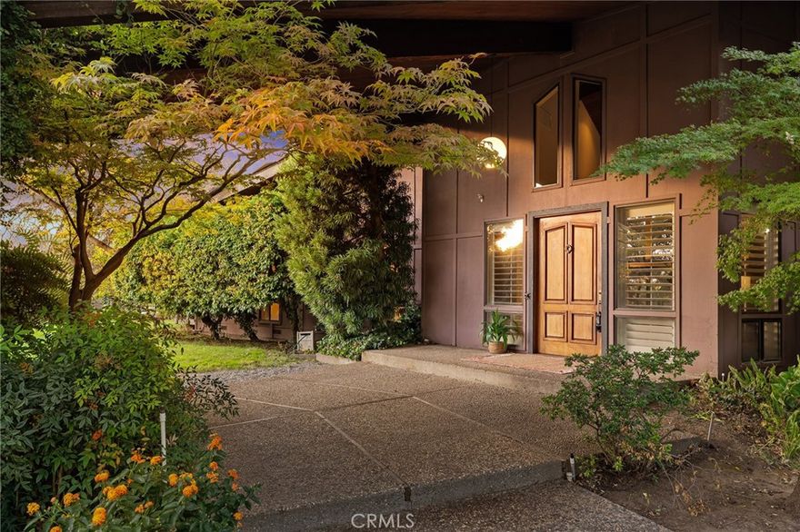 This stunning mid-century modern home is a true showstopper—an architectural gem that perfectly blends iconic design with the natural beauty surrounding it. Soaring floor-to-ceiling windows in every room invite the outdoors in, offering breathtaking views of the Gunite pool, seasonal creek, and majestic oaks. Every angle captures light, texture, and the peaceful rhythm of nature.



Step through the solid mahogany door into a grand marble-tiled entryway where warm wood-beamed ceilings and a sunken living area create an atmosphere of timeless sophistication. The vintage George Nelson bubble lamps, floor-to-ceiling rock backdrop framing the wood-burning stove, and open concept design embody true mid-century minimalism—refined, organic, and effortlessly modern.



The designer kitchen by Sue Hoss seamlessly blends style and function with thoughtful details including a spice drawer, cookie sheet cabinet, and custom appliance and trash garages. Between the kitchen and living room, the eat-in counter offers the perfect vantage point to take in the soaring windows—making you feel completely surrounded by nature even while indoors.



The primary retreat is a sanctuary of light and calm, featuring a spacious walk-in closet and a sleek, modern ensuite with striking burgundy tile and a step-down tub that frames a serene view of the outdoors. Enjoy low energy bills with oversized 16kw's of OWNED SOLAR!!



Outdoors, the magic continues. Meandering paths reveal colorful gardens, bubbling fountains, gazebos, and secluded seating areas that change beautifully with the seasons. A large cedar sauna overlooking the creek provides the ultimate space to unwind while listening to the gentle sounds of flowing water and rustling leaves—a private wellness retreat right at home.



The landscape is rich with Deodar Cedars, Aleppo Pines, Magnolia Grandiflora, Dogwood, and the brilliant golden hues of Ginkgo Biloba. A fully equipped greenhouse—with watering, evaporative cooling, and air-recirculating systems—keeps your gardens thriving year-round.



The property’s 2.9 acres include a barn with kennels, workbenches, and storage, plus a second metal barn near the creek that once housed horses. With 4 bedrooms, 2.5 baths, a large sauna, and owned solar, this home offers the rare combination of architectural distinction, modern comfort, and peaceful country living—all just minutes from town.