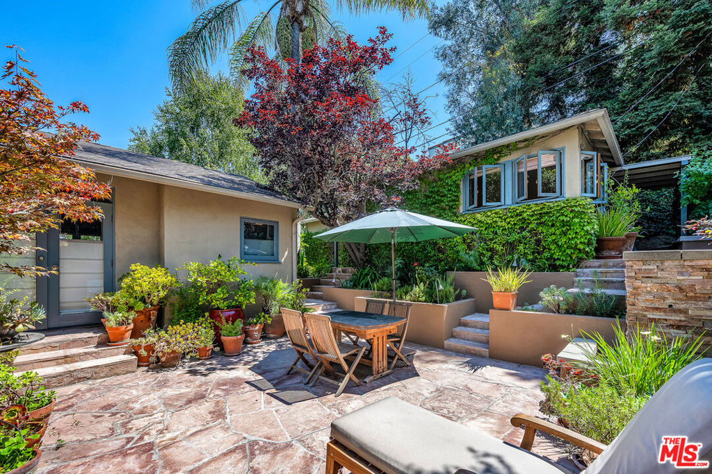 This exceptional property features a beautifully remodeled 2 bedroom, 2 bath main home plus a separate, permitted structure with a 3/4 bath and its own private driveway. The meticulously updated home radiates sleek, sunlit charm throughout. Vaulted ceilings and generous skylights fill the space with natural light, while hardwood floors and central air conditioning enhance the welcoming atmosphere. The recently renovated kitchen offers ample storage, stainless steel appliances, and a convenient breakfast bar. In addition, there is direct access to the two-car garage and laundry area. The expanded primary bedroom opens to the lush private yard and spa, providing an ideal retreat. The luxurious primary bath features a steam shower and a separate soaking tub for ultimate relaxation. The second bedroom, complete with a built-in desk, also opens to the serene patio area. The guest bath has been beautifully remodeled to match the home's sophisticated design. Additionally, a permitted structure with a 3/4 bath provides a versatile space perfect for an office, guest room or recording studio. Located on a spacious corner lot, in a prime section of the Hollywood Hills, this hidden gem is just moments from major studios and the Hollywood Bowl.
